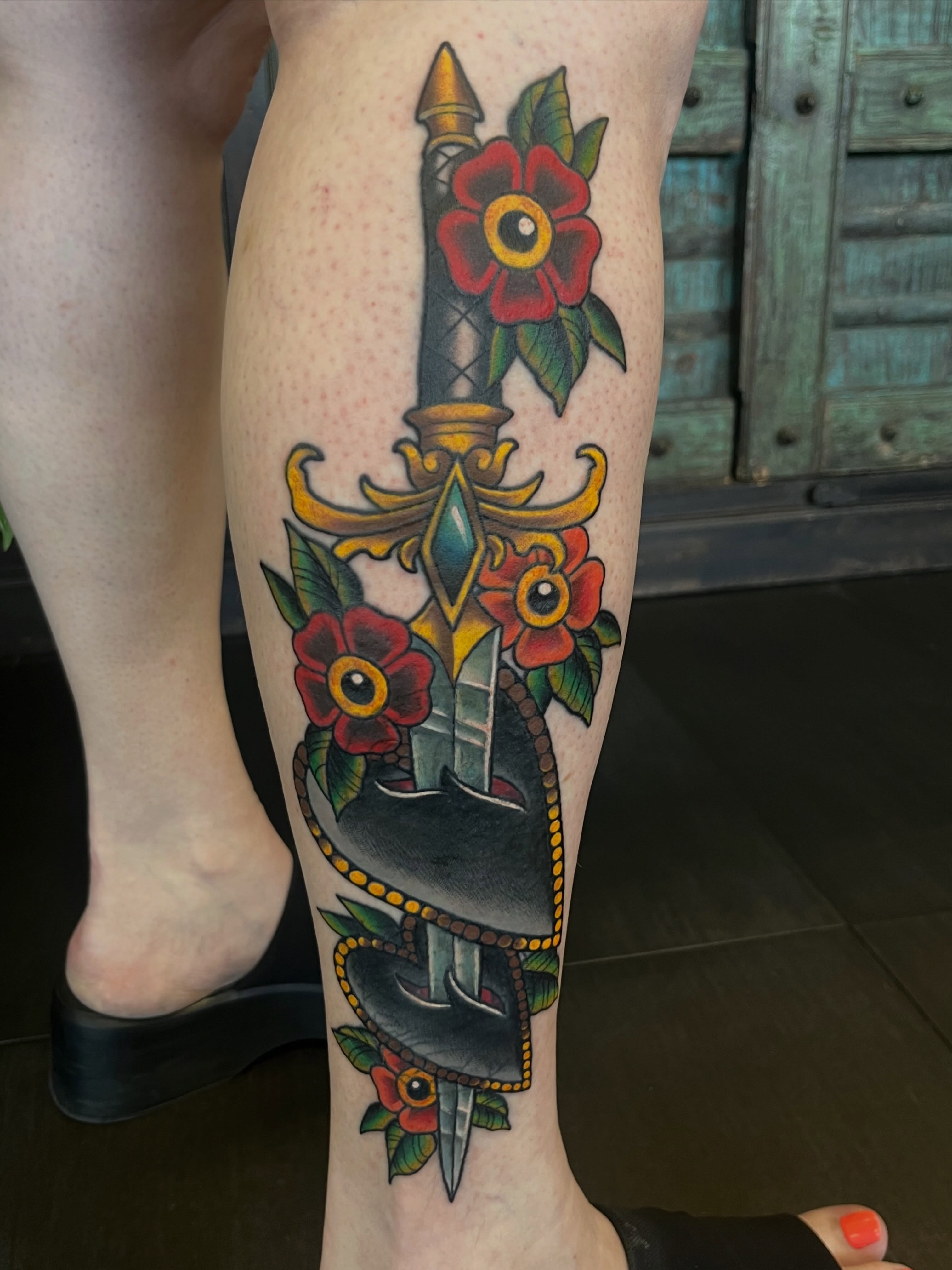 Sword and flowers American traditional tattoo on the calf by Allie Tippets, Gilbert, Arizona