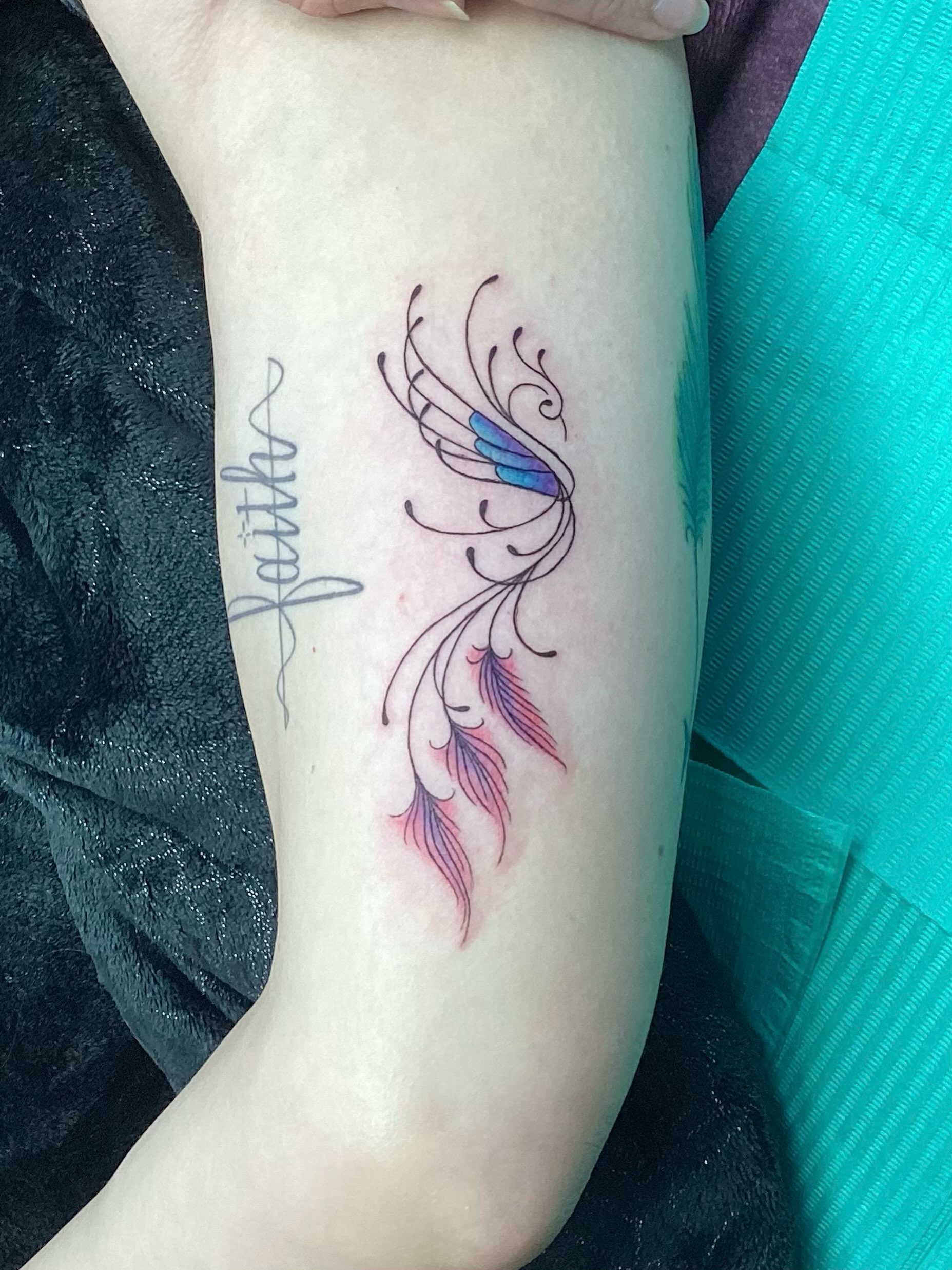 Feather and script fine line tattoo on the forearm by Amanda Plavan