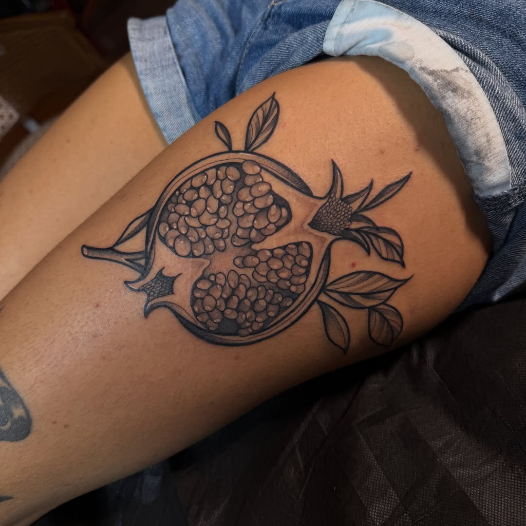 Pomegranate black and grey tattoo on the thigh by Allison