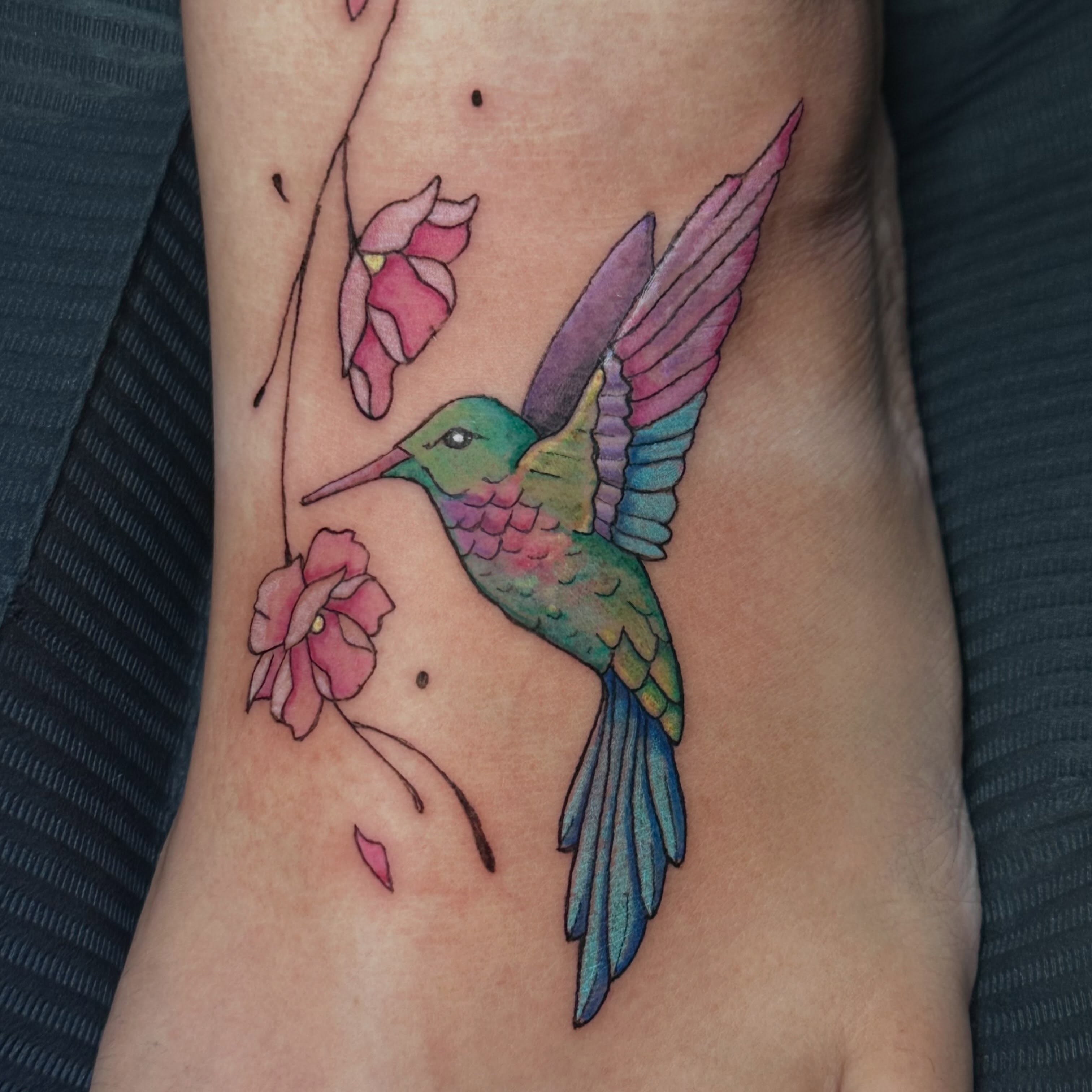 Hummingbird and flowers watercolor tattoo on the forearm by Sam, Mount Laurel, New Jersey