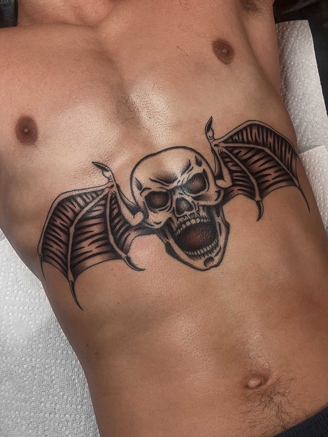 Skull with wings black and grey tattoo on the ribs by Las Vegas Tattoo Artist