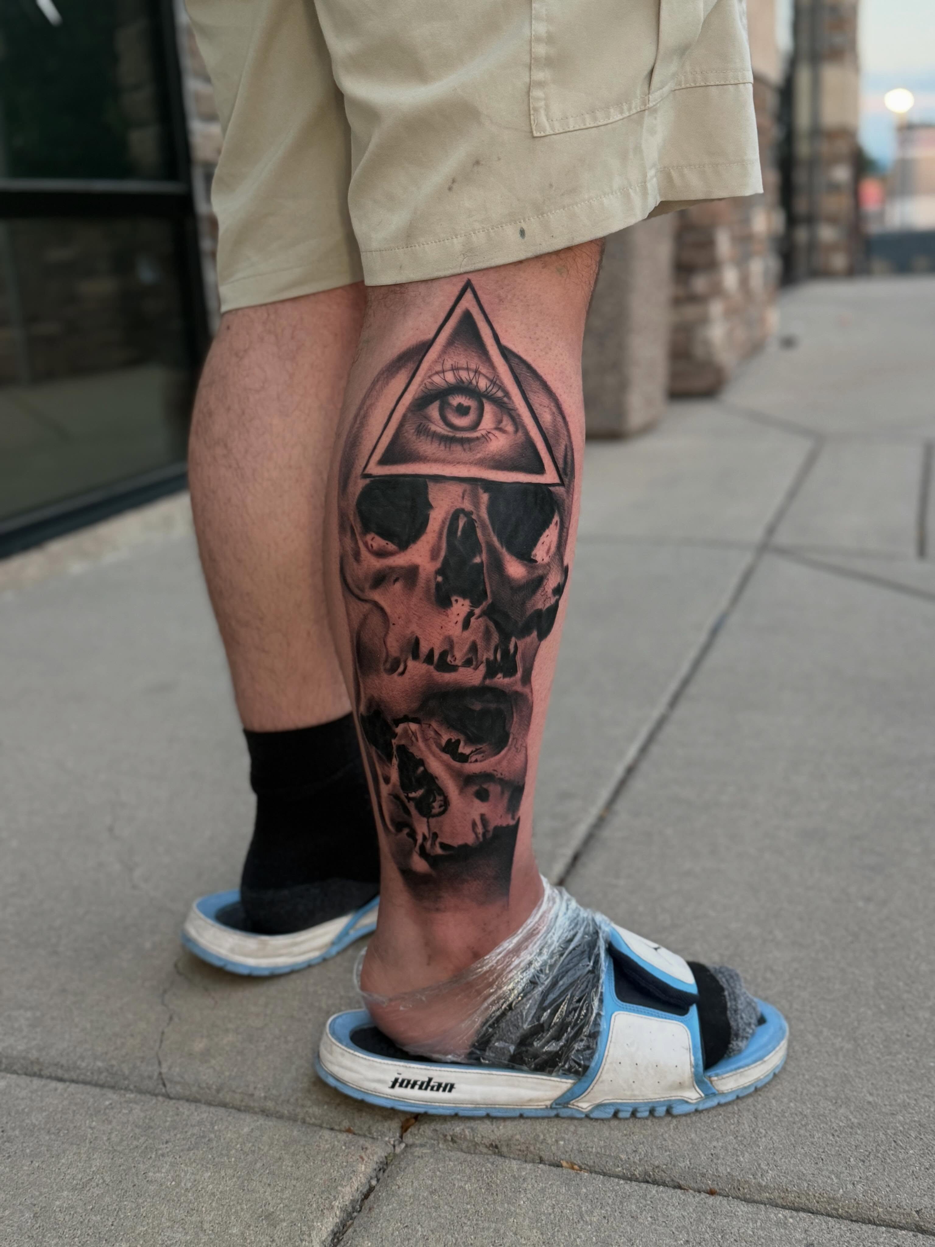 Skull with all-seeing eye realism tattoo on the calf by Adrián Banuelos