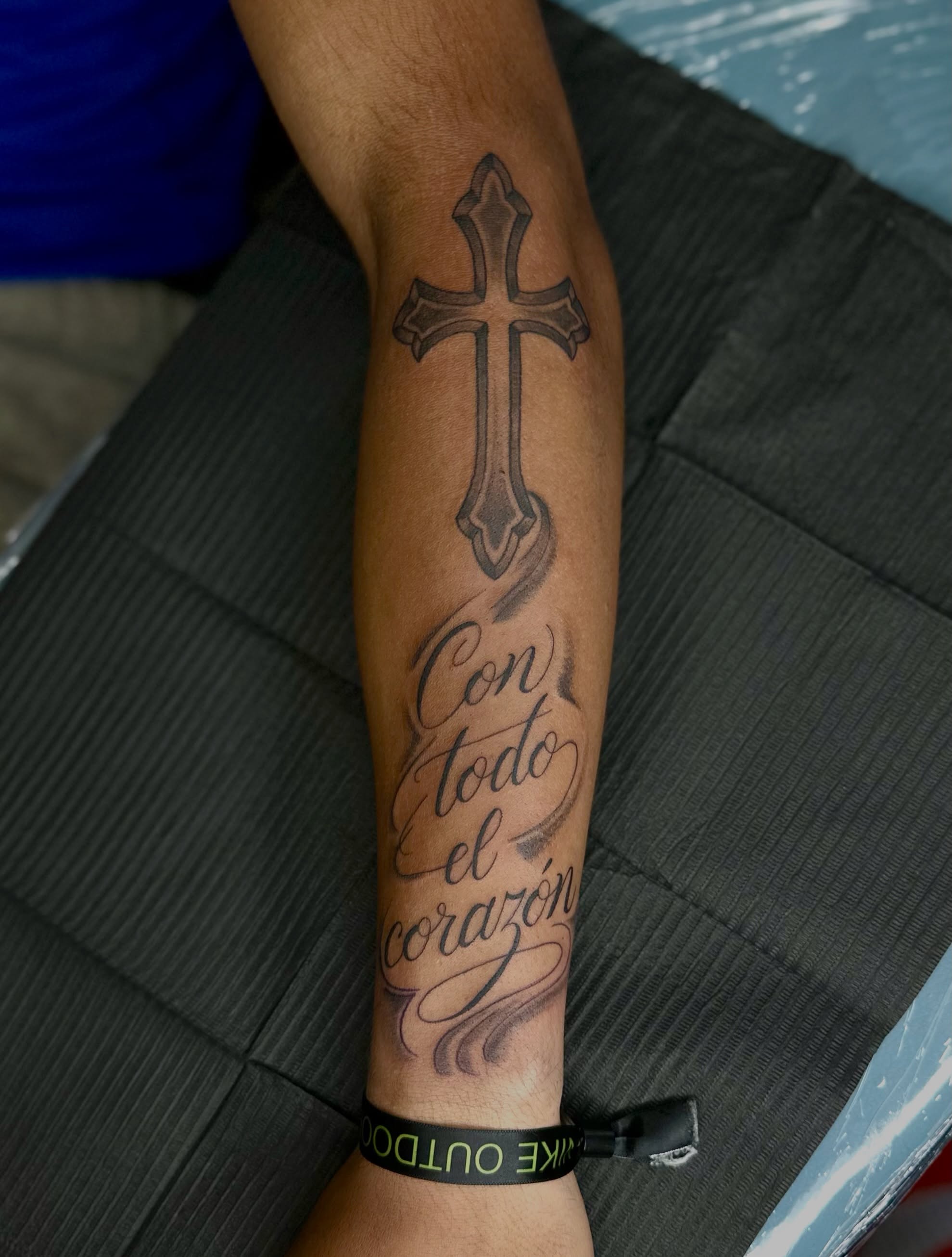 Cross and script black and grey tattoo on the forearm by NuNu
