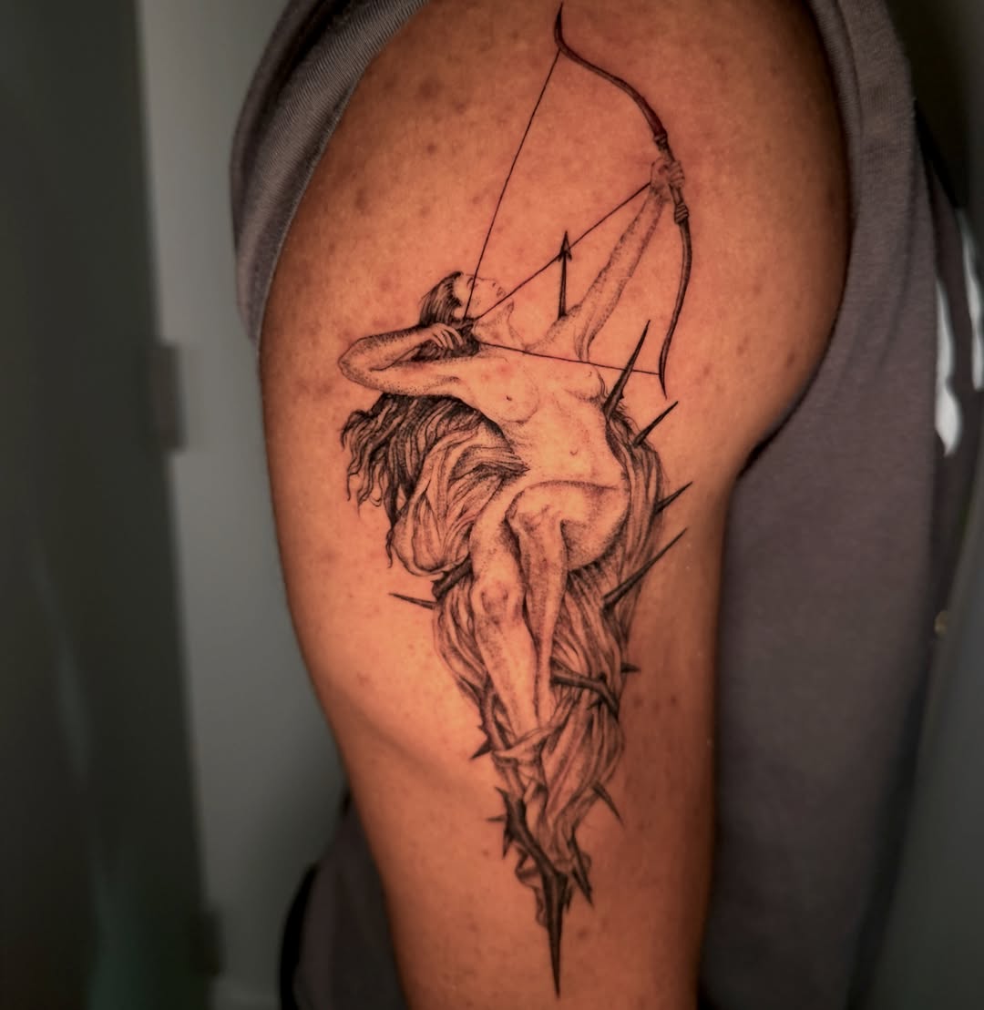 Archer black and grey tattoo on the upper arm by Syd Cheyenne