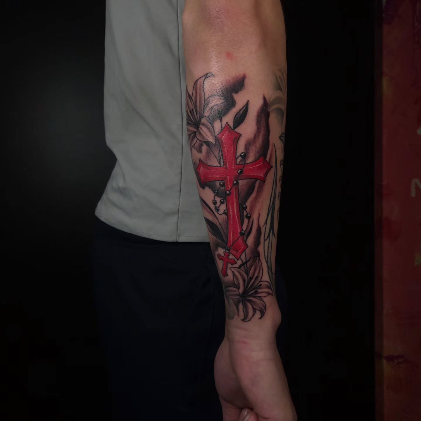 Cross and flowers realism tattoo on the forearm by Buk