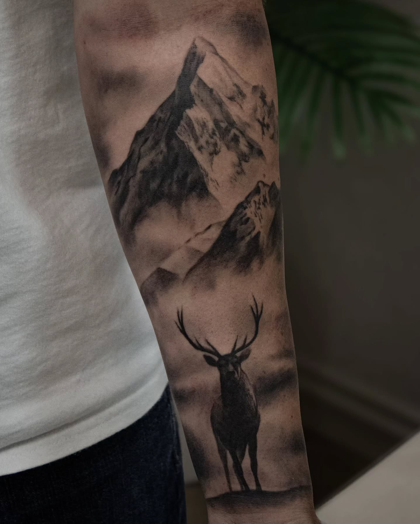 Mountain and stag realism tattoo on the forearm by Erik Bonilla