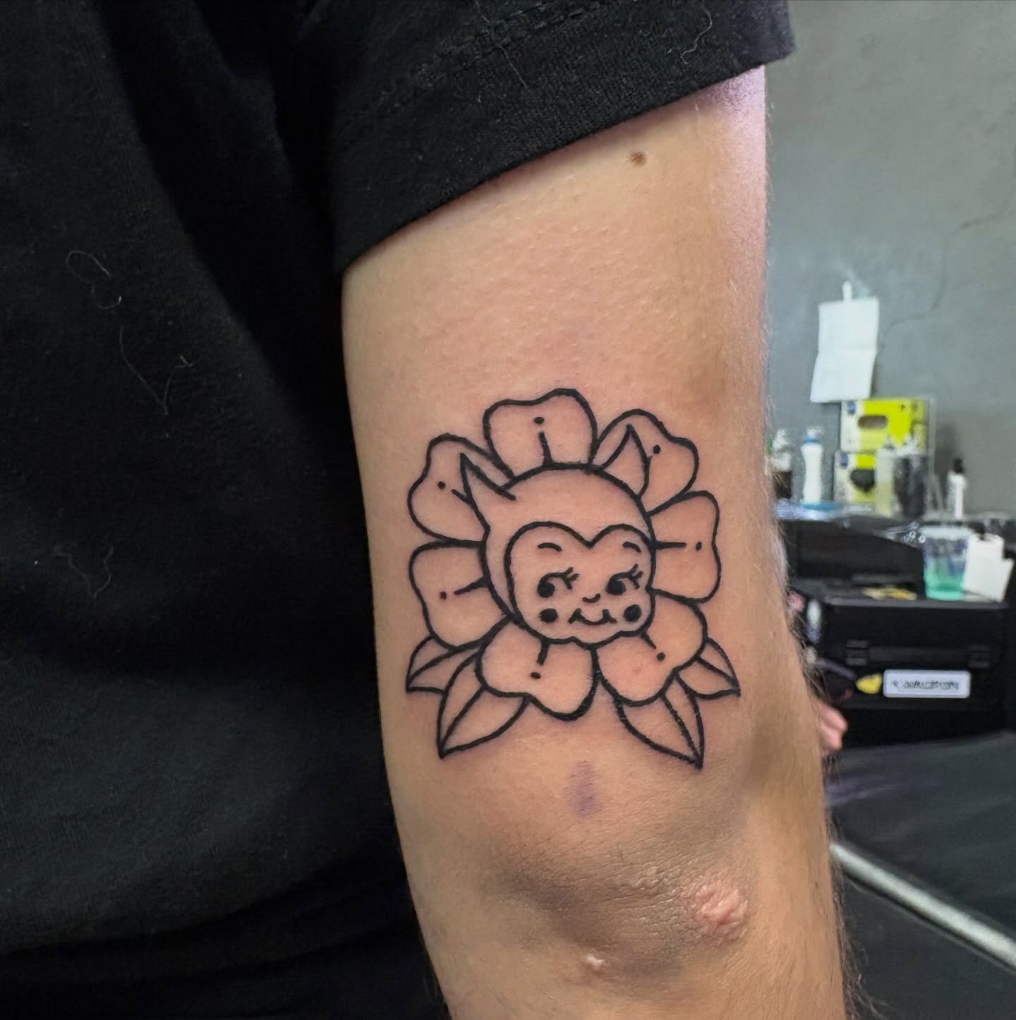 Flower with cartoon character black and grey tattoo on the forearm by Hailee Wallace Brussow