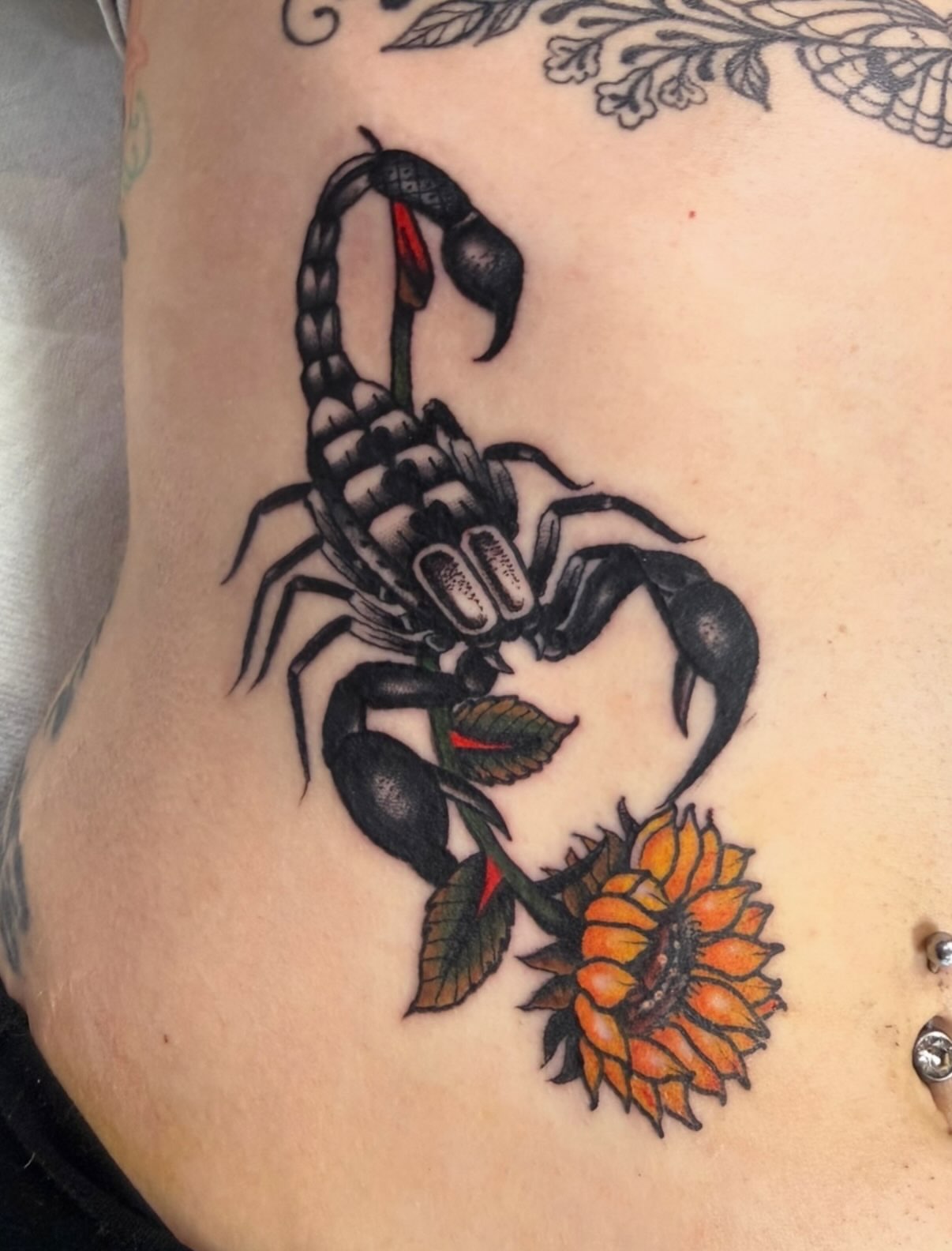 Scorpion and sunflower American traditional tattoo on the thigh by David Evans