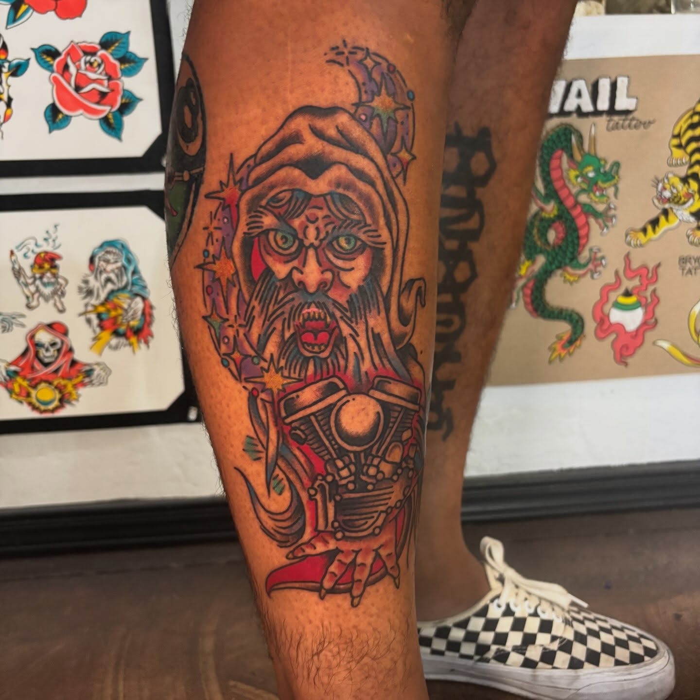 Bearded man with motorcycle engine American traditional tattoo on the leg by bryce duval