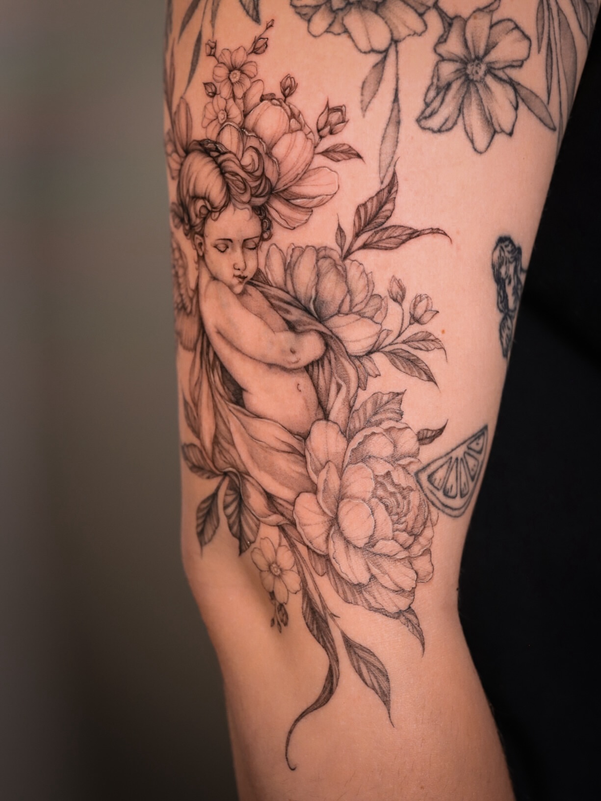 Cherub and flowers realism tattoo on the forearm by Caroline + Utah Tattoo Artist