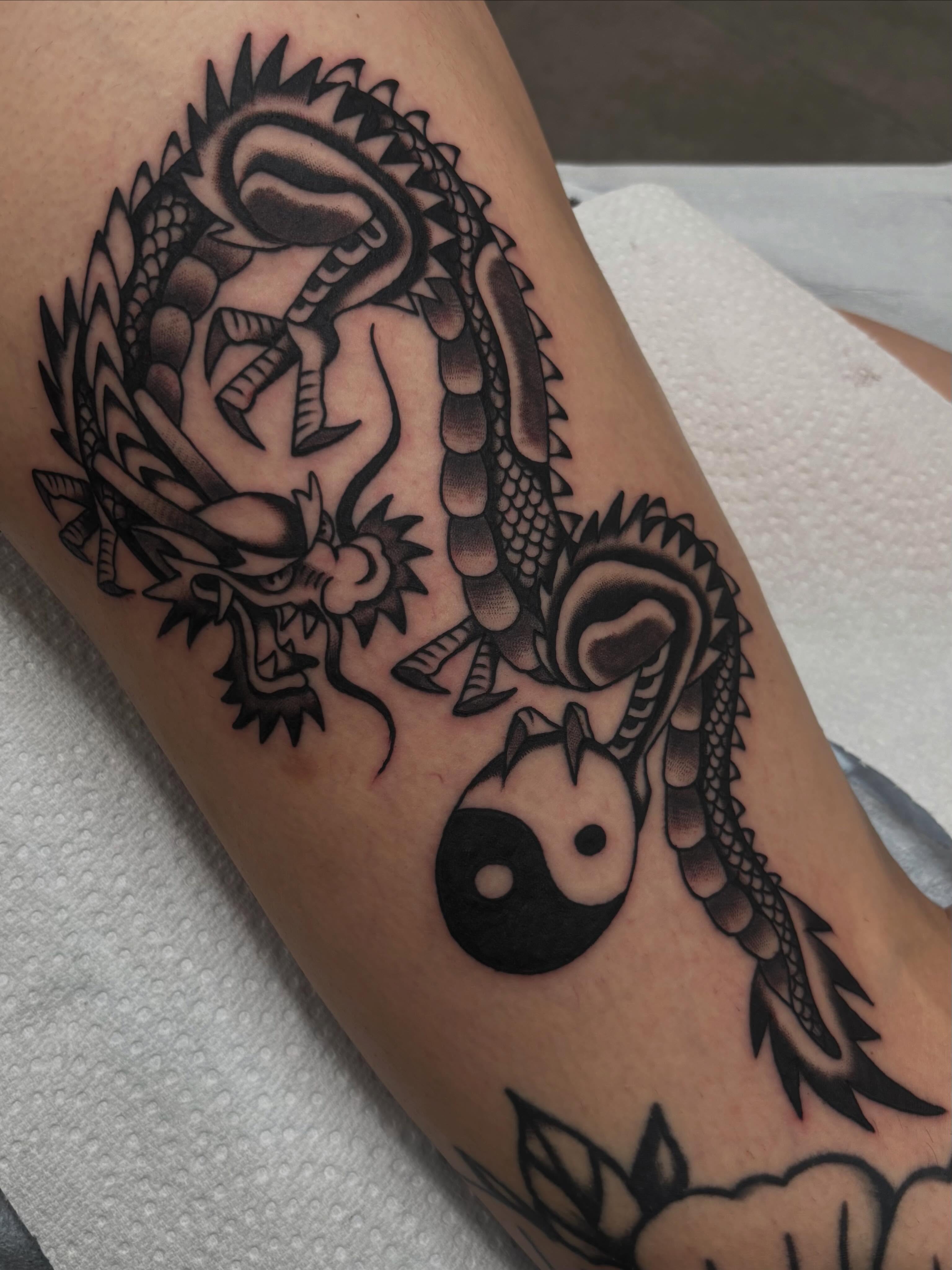 Dragon and yin-yang black and grey tattoo on the forearm by Claire Anderson