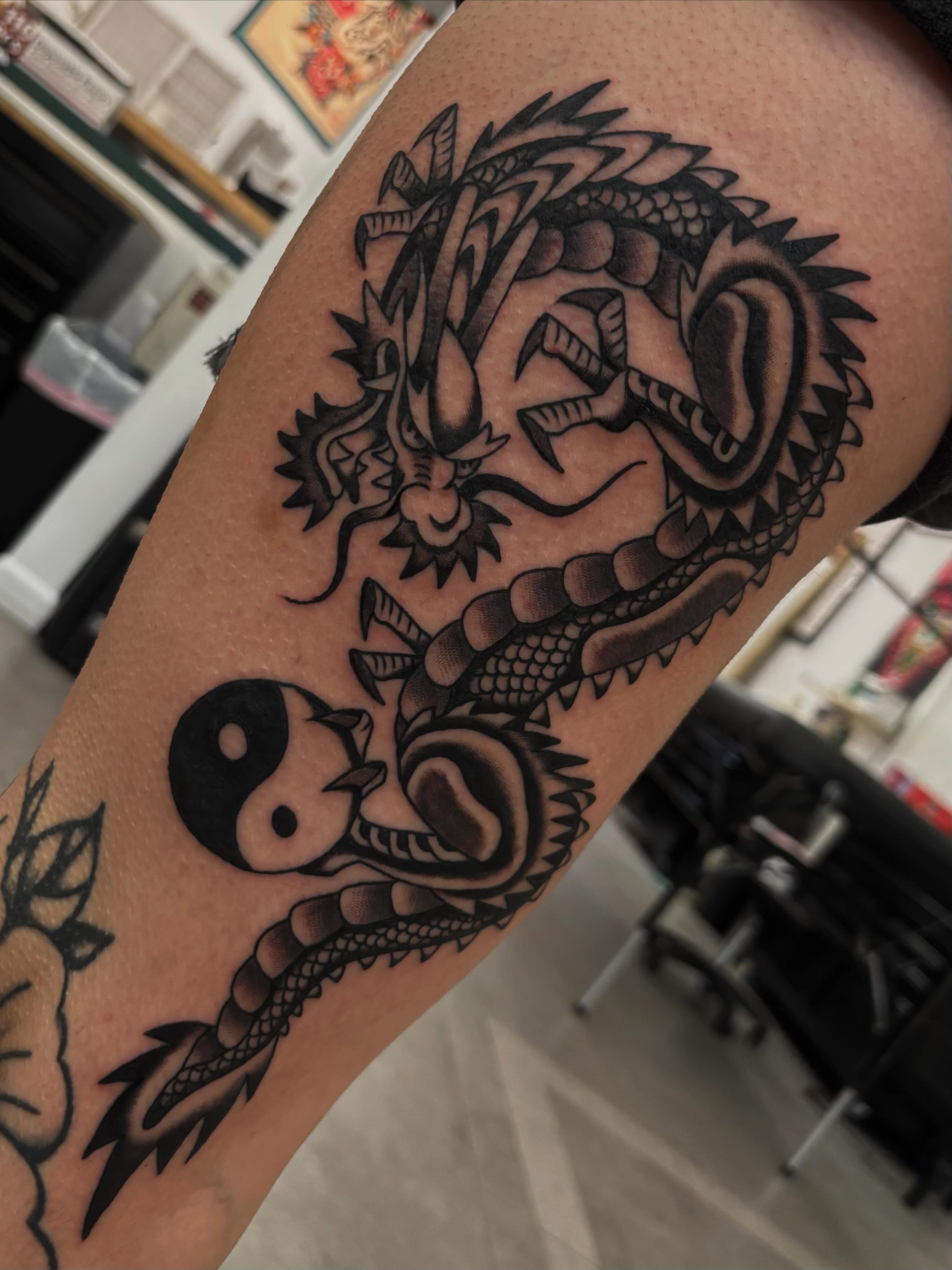 Dragon and yin-yang black and grey tattoo on the forearm by Claire Anderson