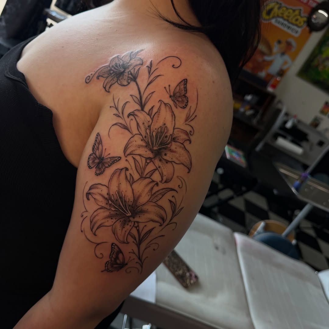 Lilies and butterflies dotwork tattoo on the shoulder by Nina Nichole