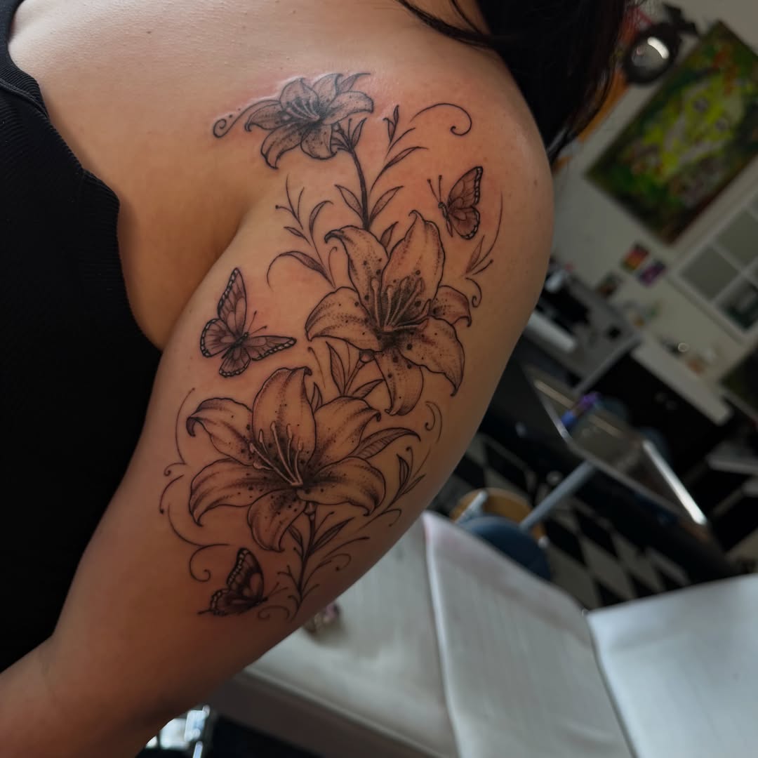 Lilies and butterflies black and grey tattoo on the shoulder by Nina Nichole