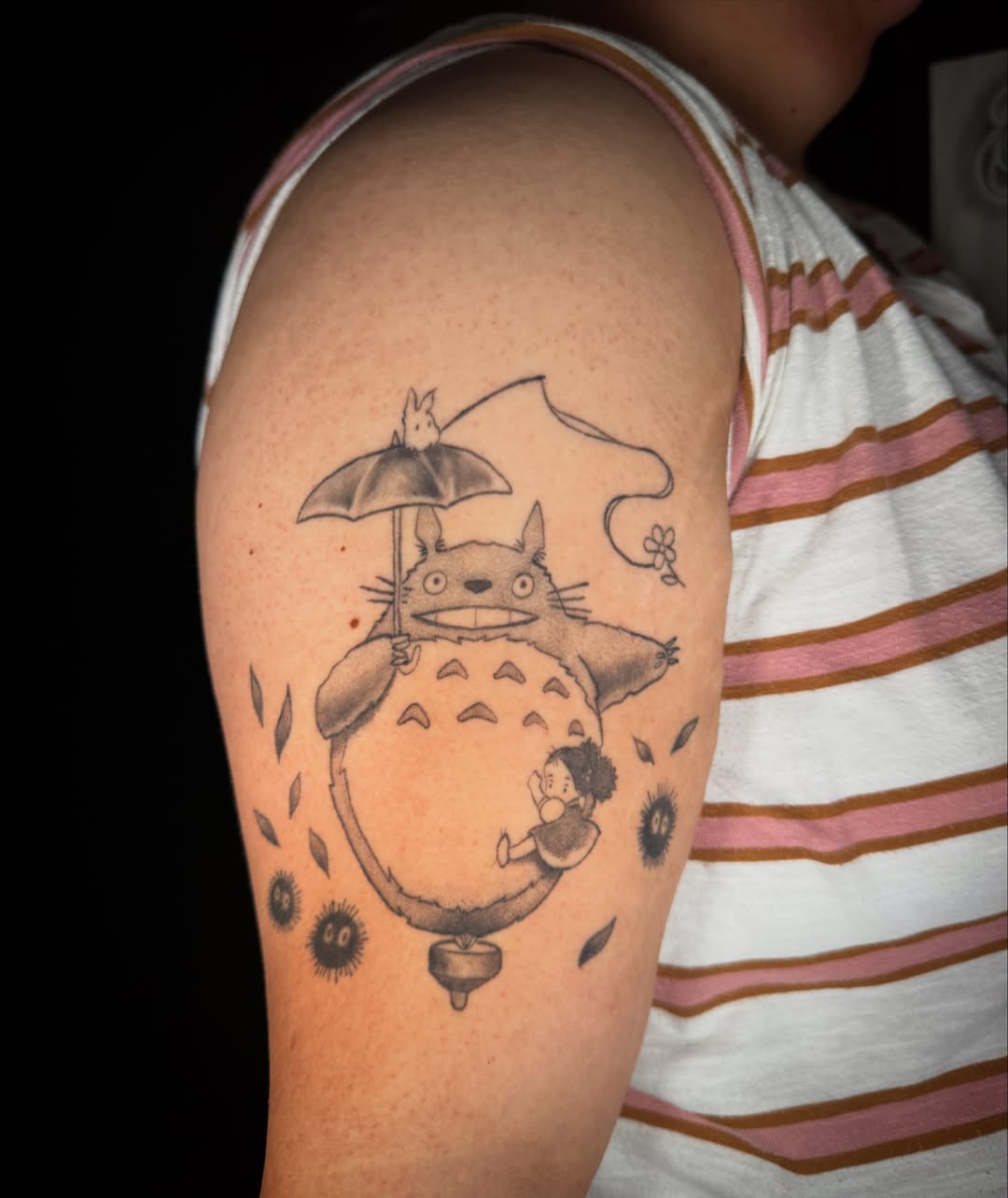 Totoro and child black and grey tattoo on the upper arm by Monica Gonzalez