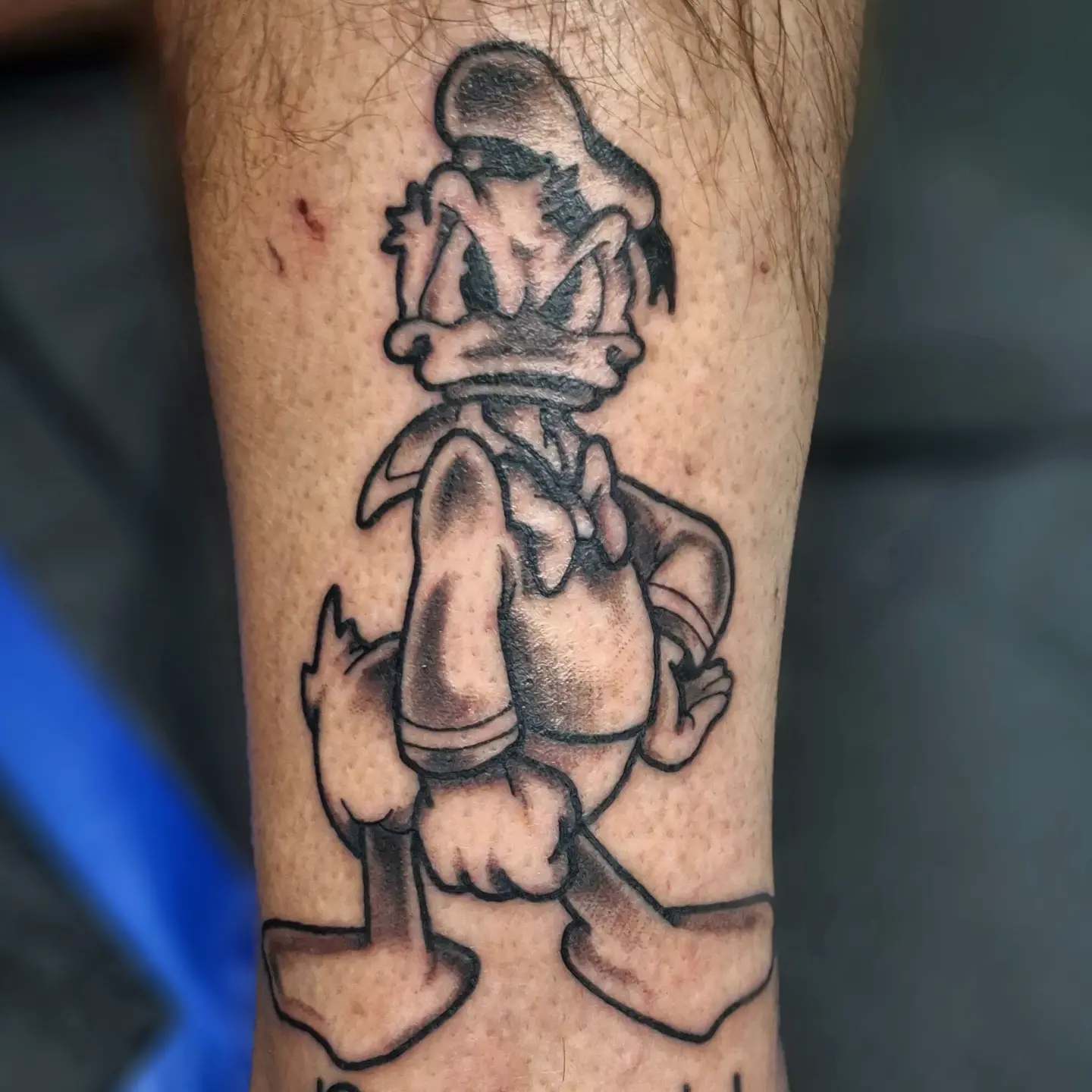 Donald duck black and grey tattoo on the forearm by Jake Mincey