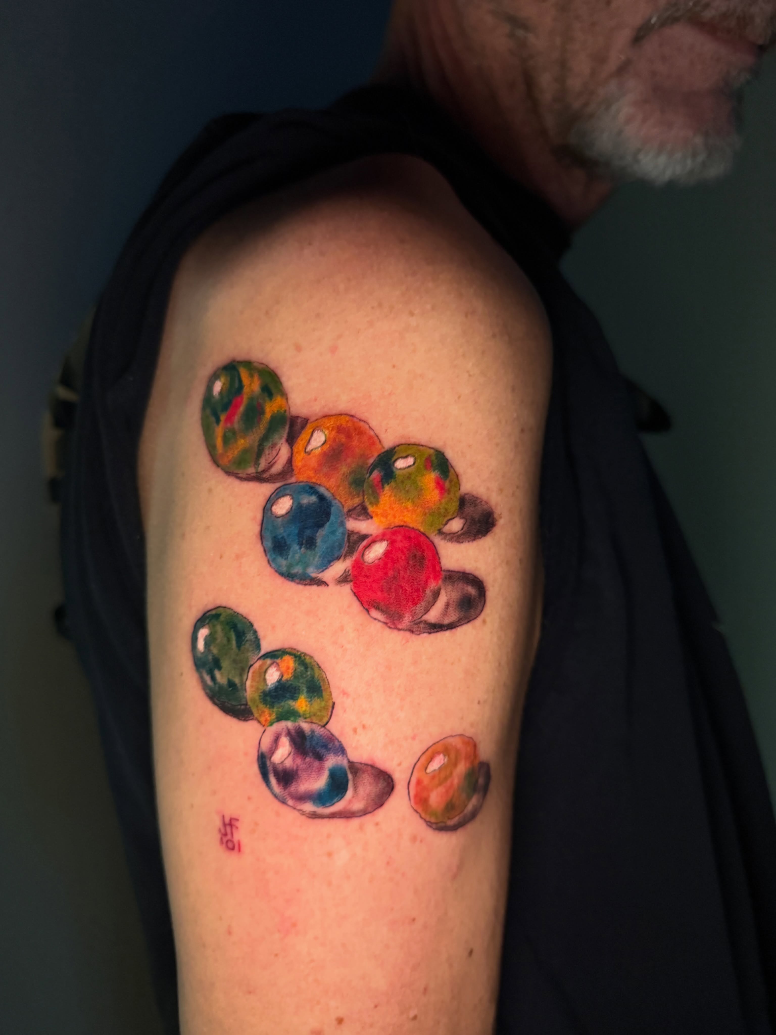 Marbles watercolor tattoo on the shoulder by spikecitytattoo