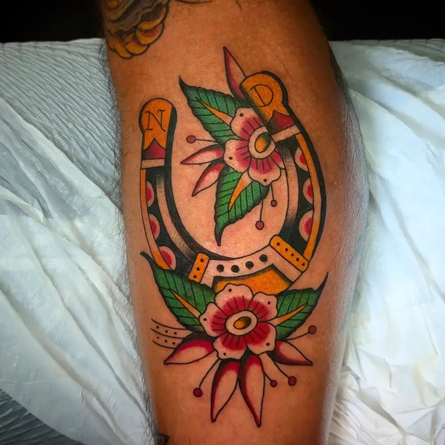 Horseshoe and flowers American traditional tattoo on the leg by joseph palladino