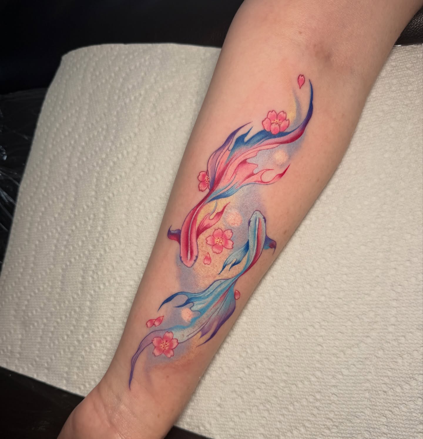 Cherry blossoms and fish watercolor tattoo on the forearm by Lyndze Masters