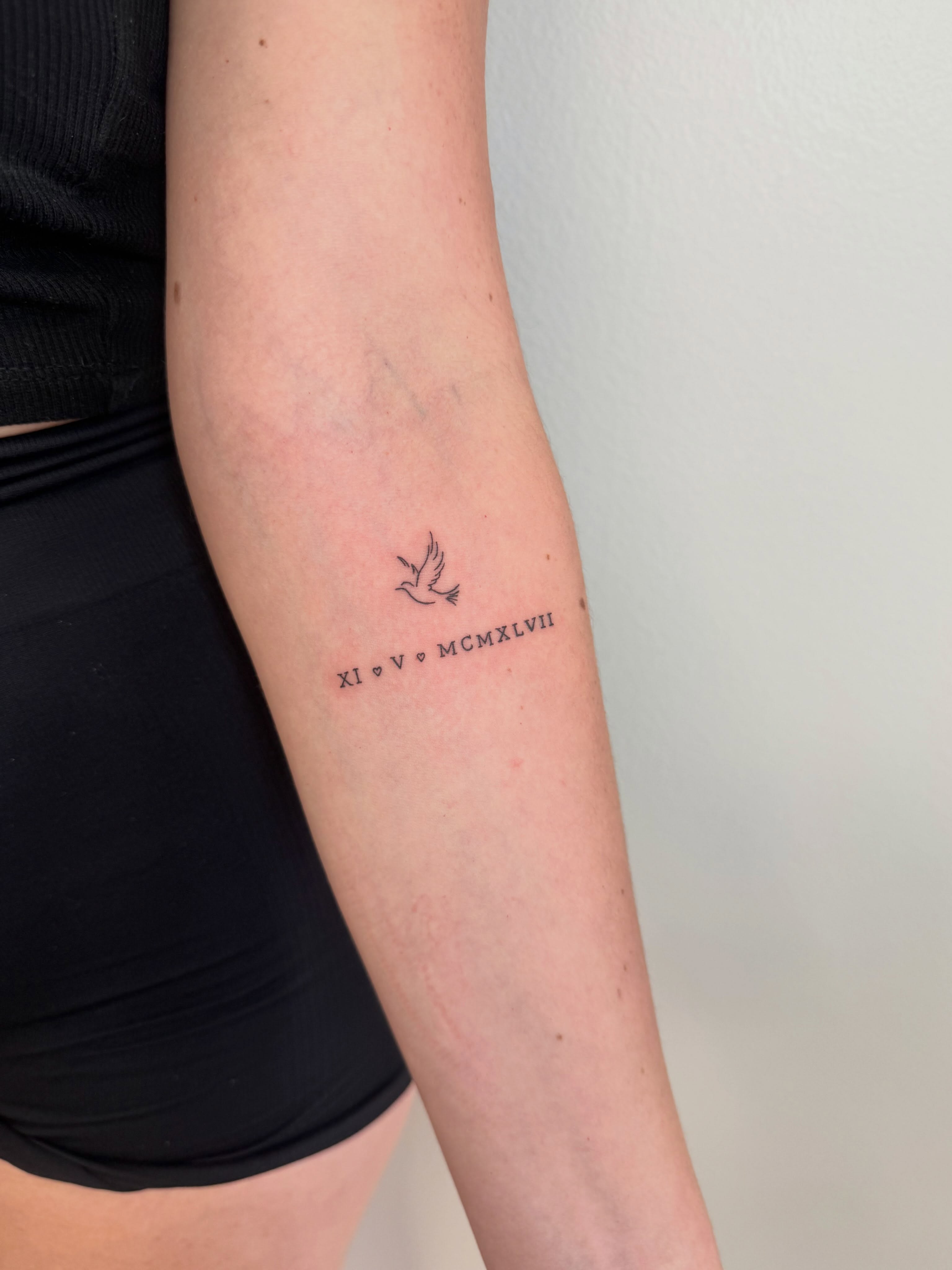 Bird and Roman numerals fine line tattoo on the forearm by Angela Nery, South Jordan, Utah