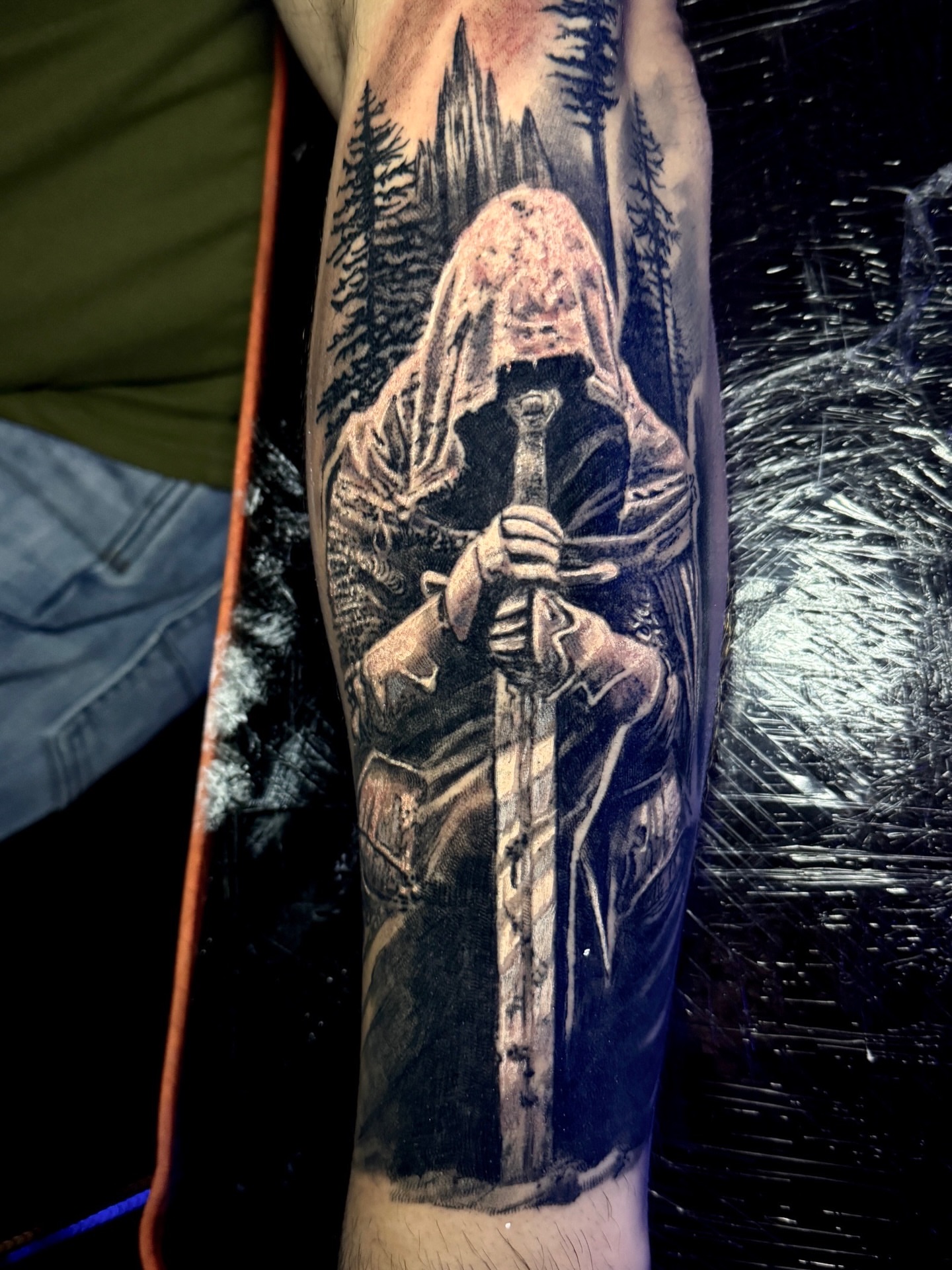 Hooded figure with sword realism tattoo on the forearm by Jarrod Gatzke