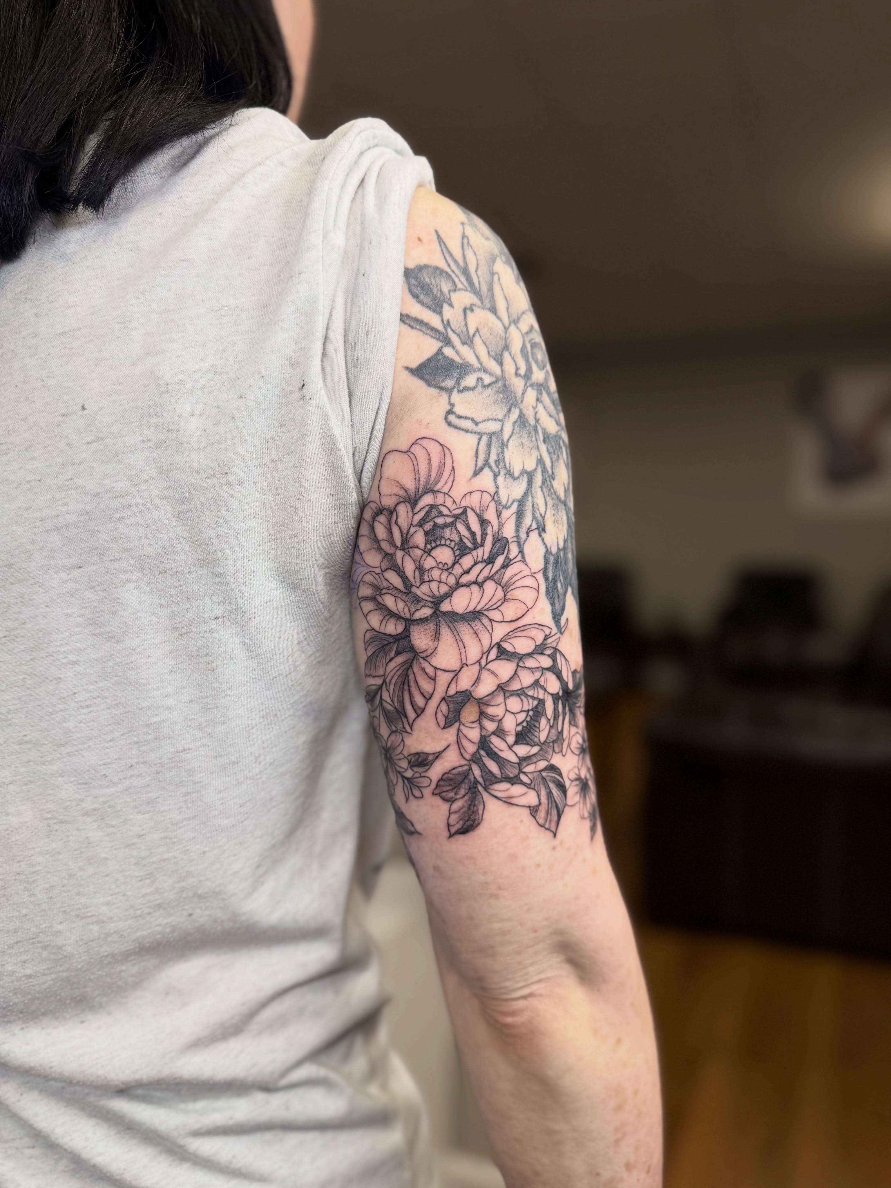 Floral bouquet black and grey tattoo on the upper arm by Skylar Sheeley