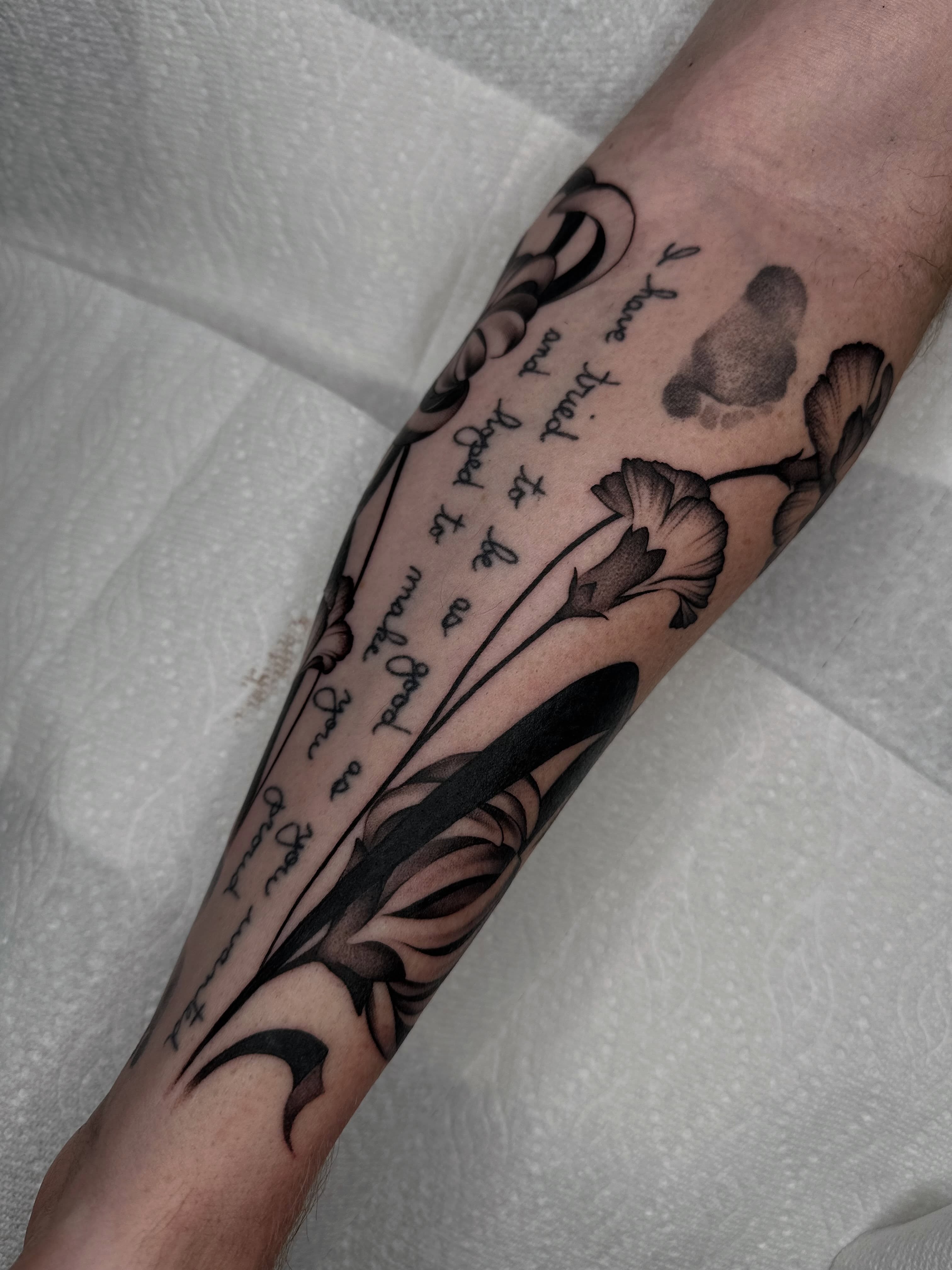 Flowers and script black and grey tattoo on the forearm by Aleksandra