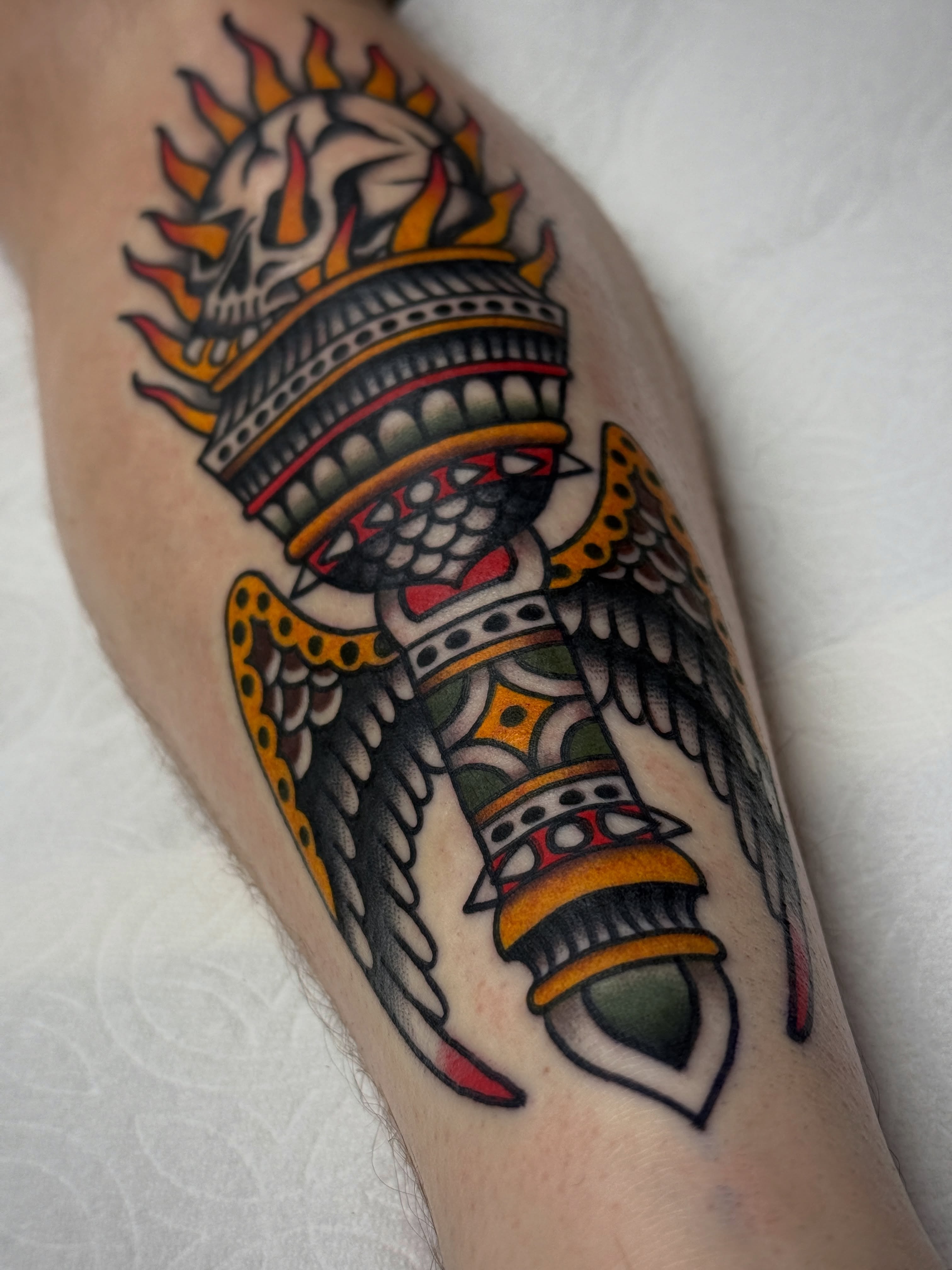 Flame-topped skull with wings American traditional tattoo on the forearm by Jordan Allen