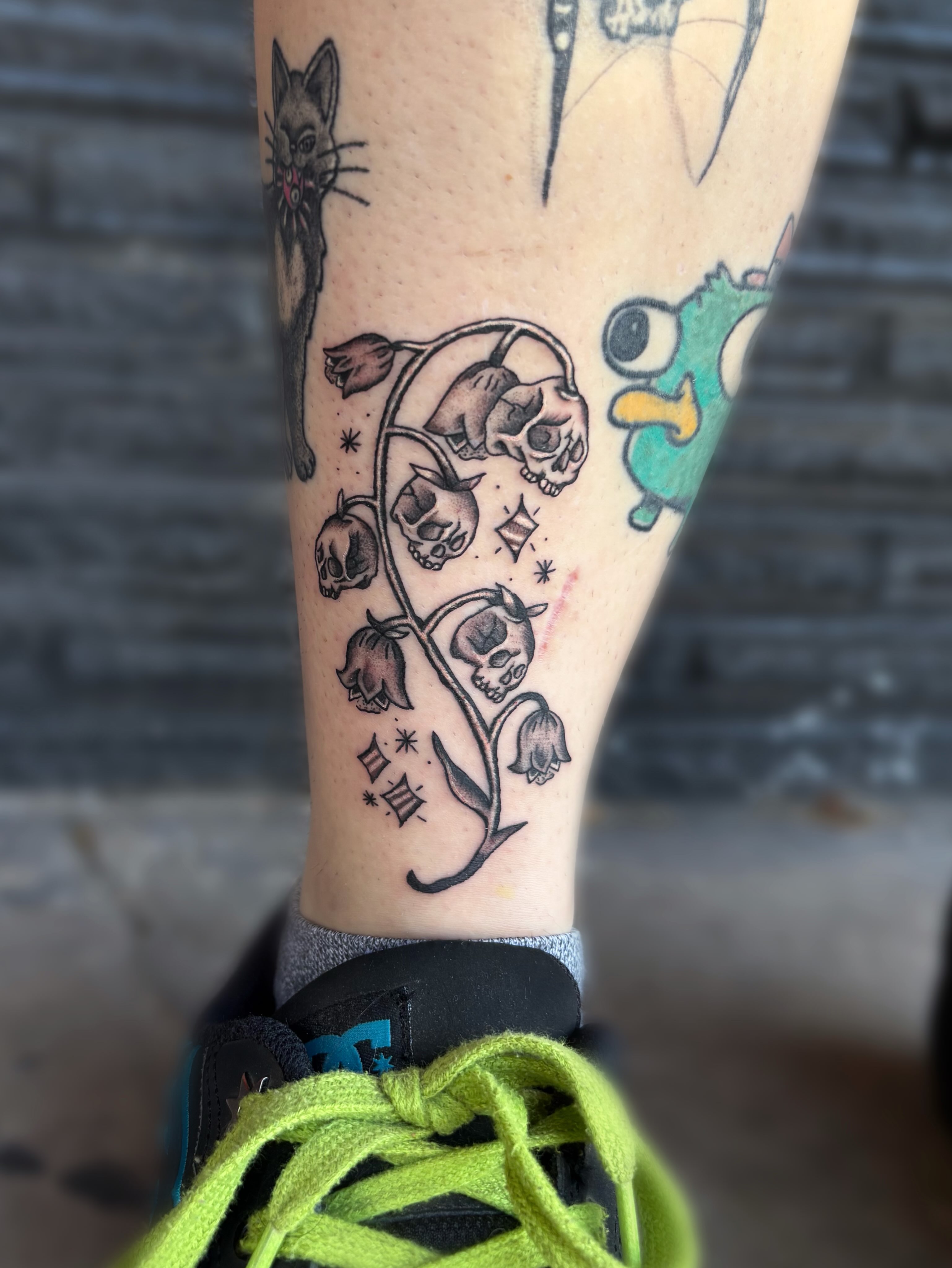 Skulls and flowers American traditional tattoo on the forearm by Ava Brady Tattoos