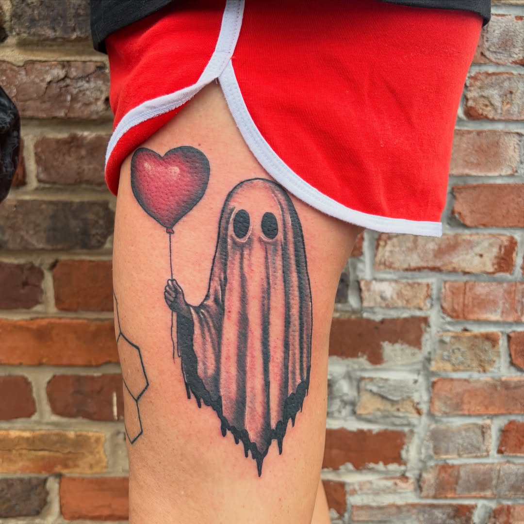 Ghost with heart balloon black and grey tattoo on the thigh by Vudu Tattooer