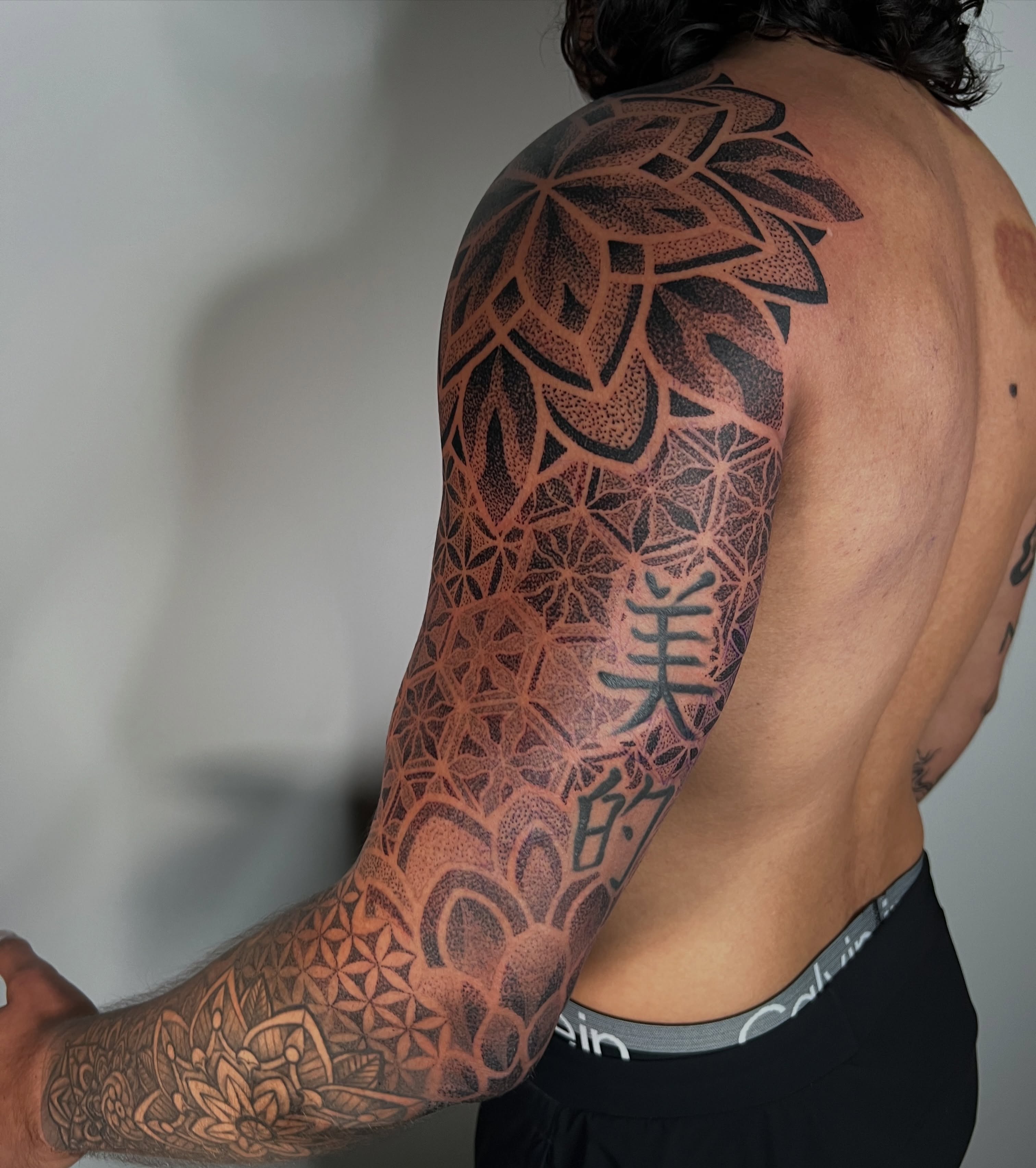Geometric patterns dotwork tattoo on the upper arm by Riley