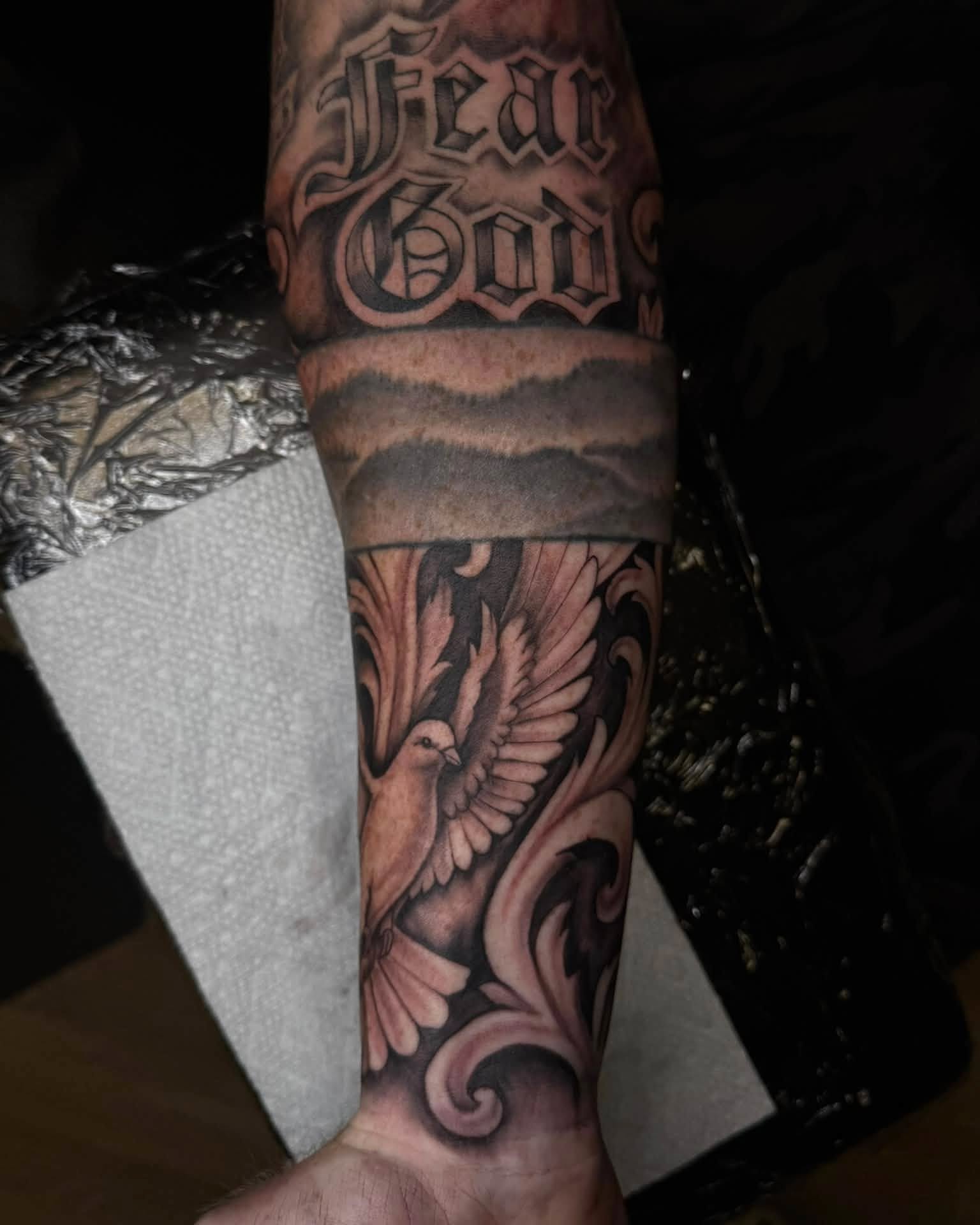 Dove and floral black and grey tattoo on the forearm by Madison Jasso