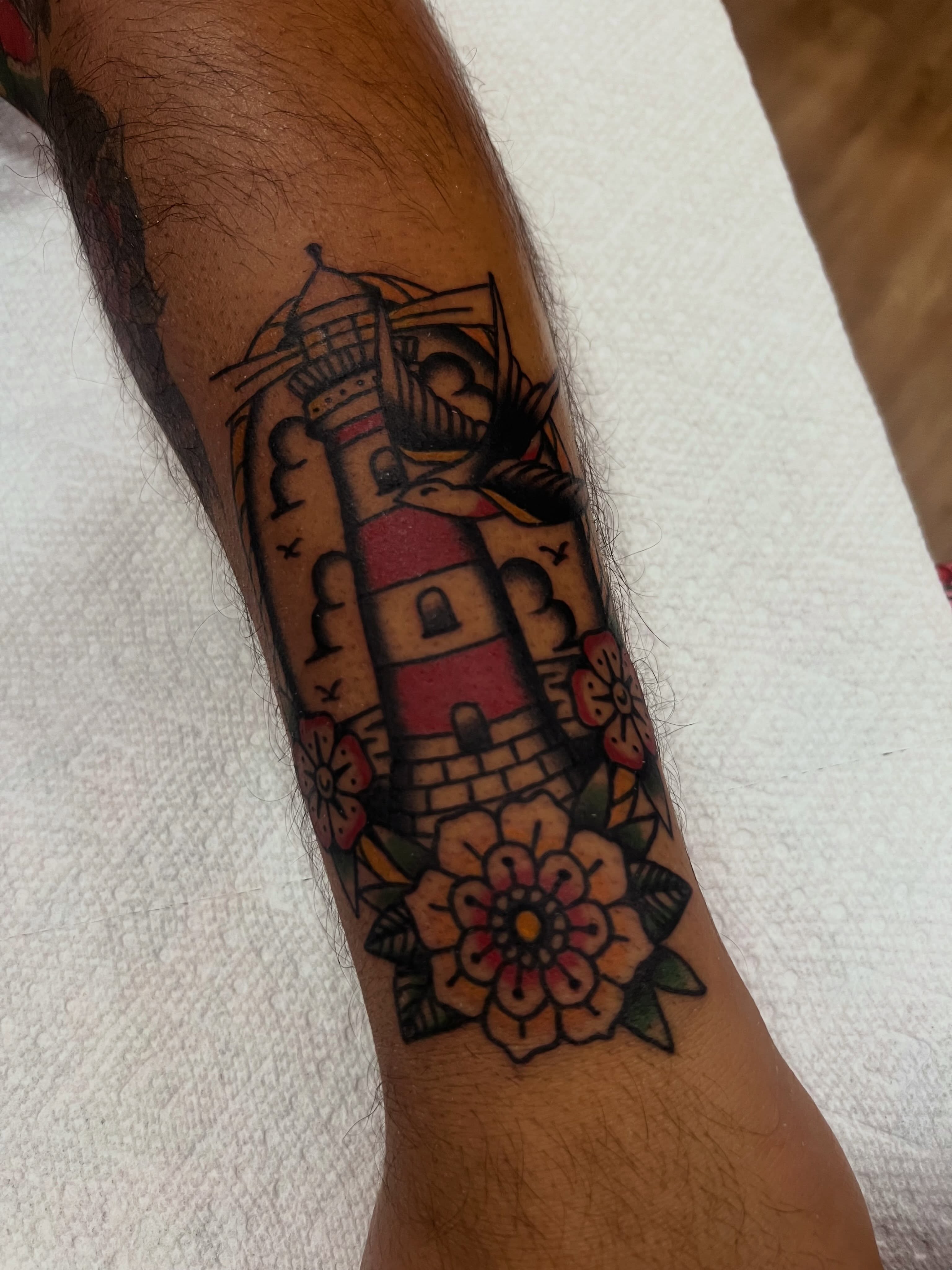 Lighthouse and flowers American traditional tattoo on the forearm by Samantha Citer