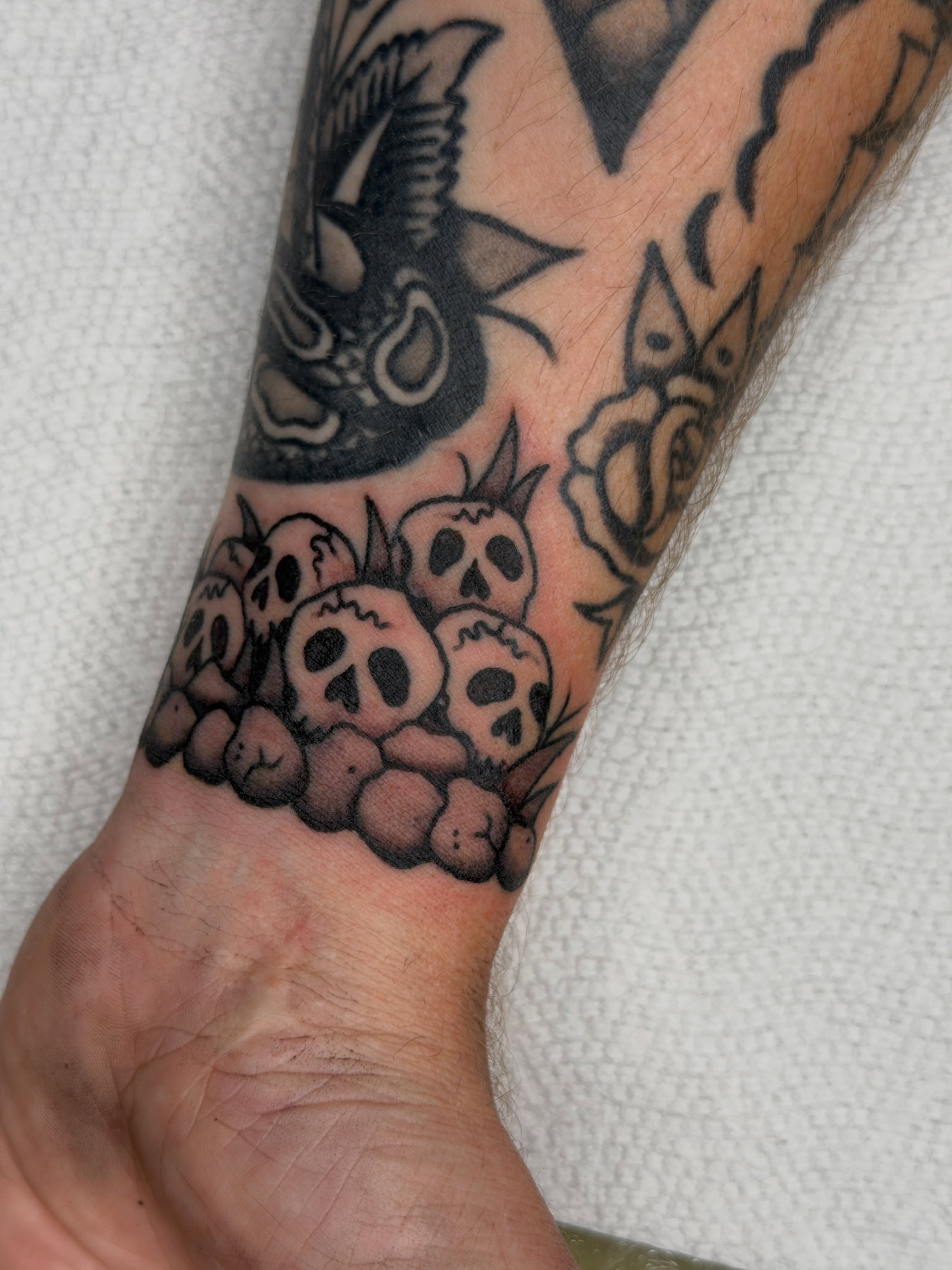 Skulls American traditional tattoo on the forearm by Andrew Storm
