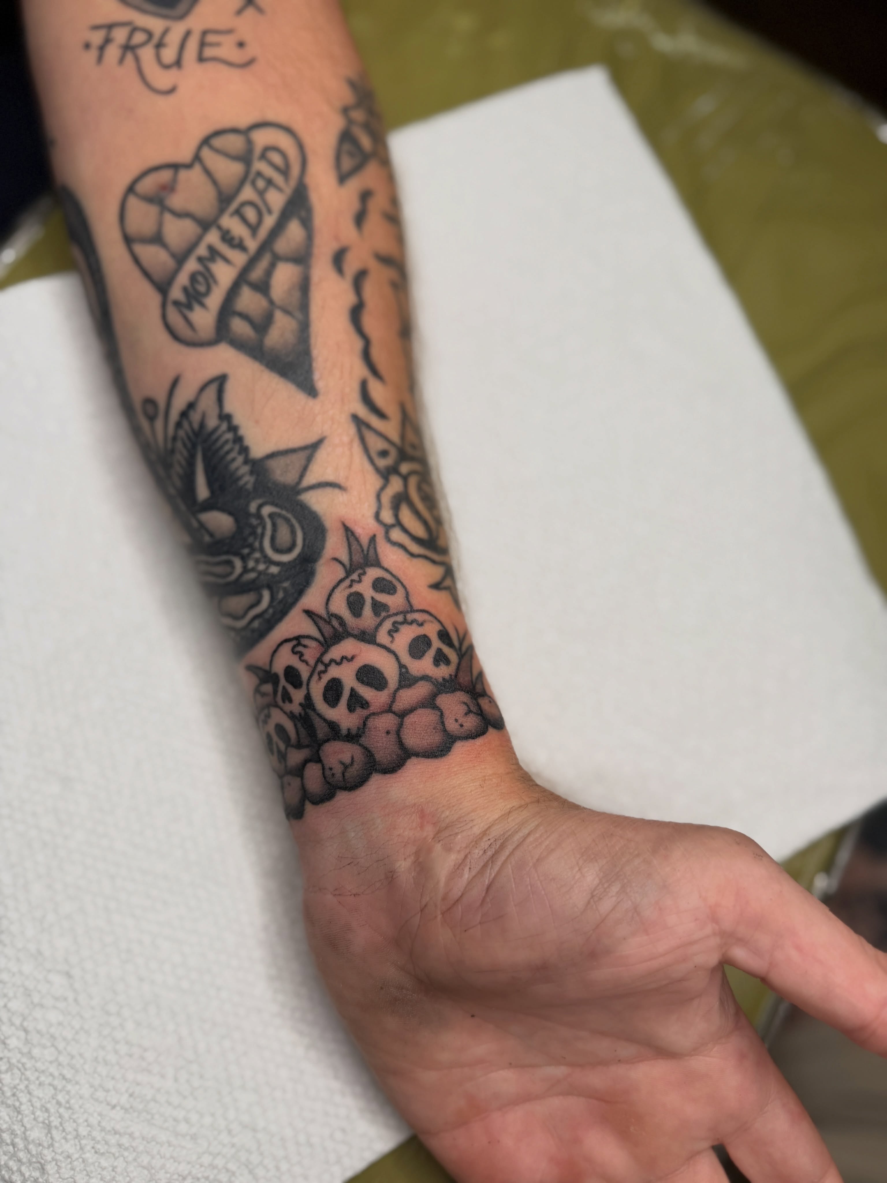 Skulls and roses American traditional tattoo on the forearm by Andrew Storm