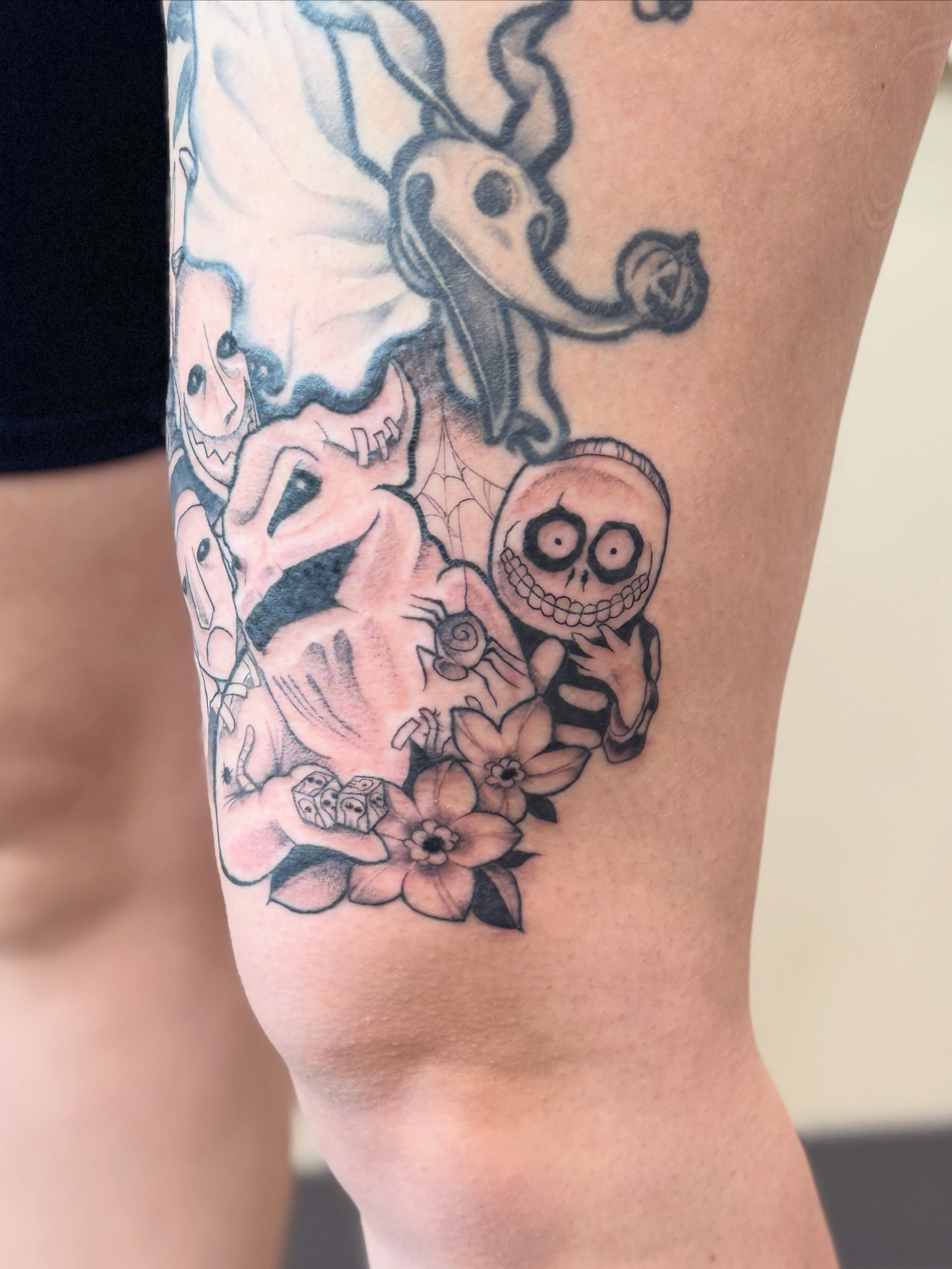 Skulls and flowers black and grey tattoo on the thigh by Rebecca Rose