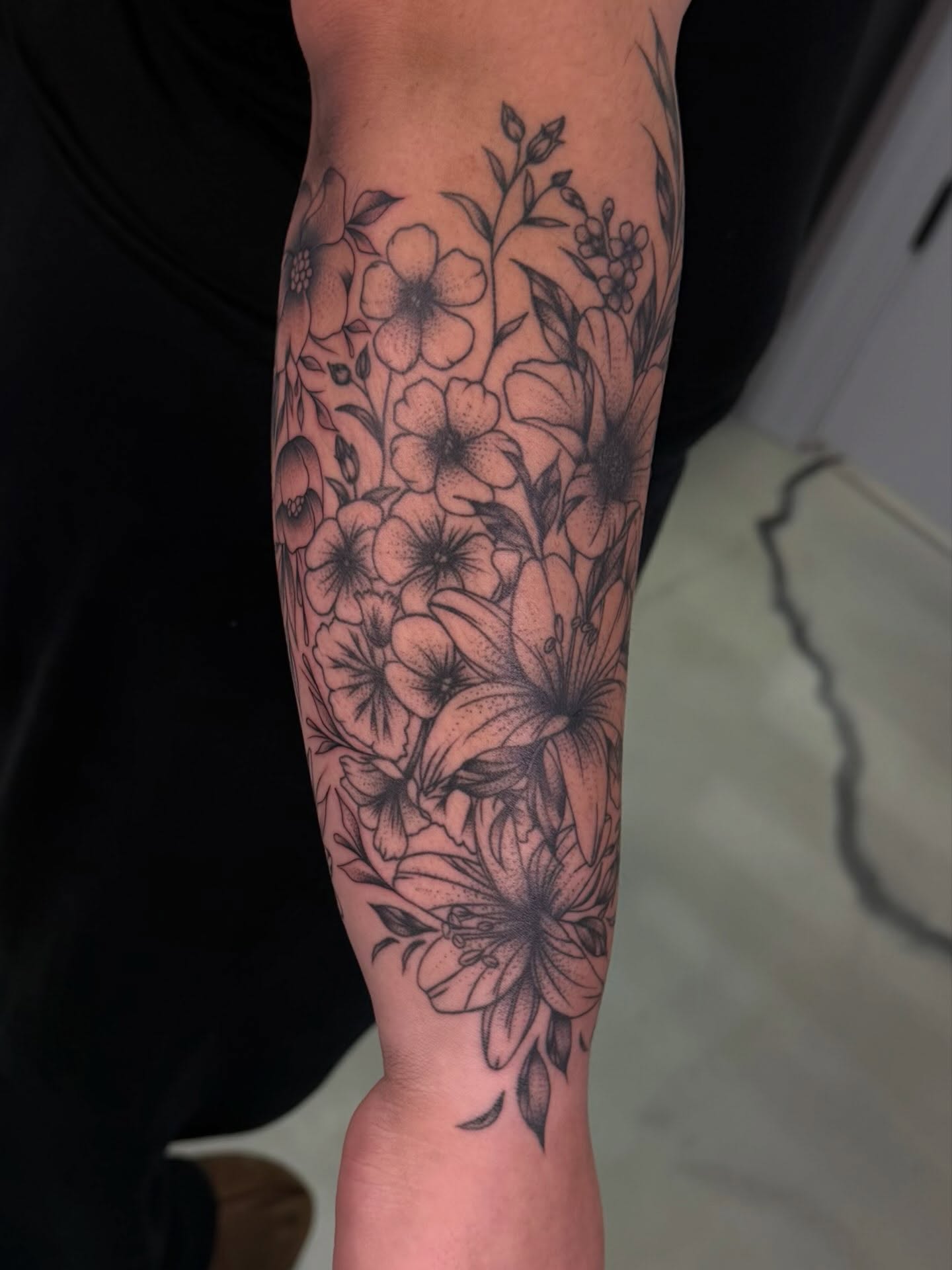 Floral bouquet black and grey tattoo on the forearm by haylie