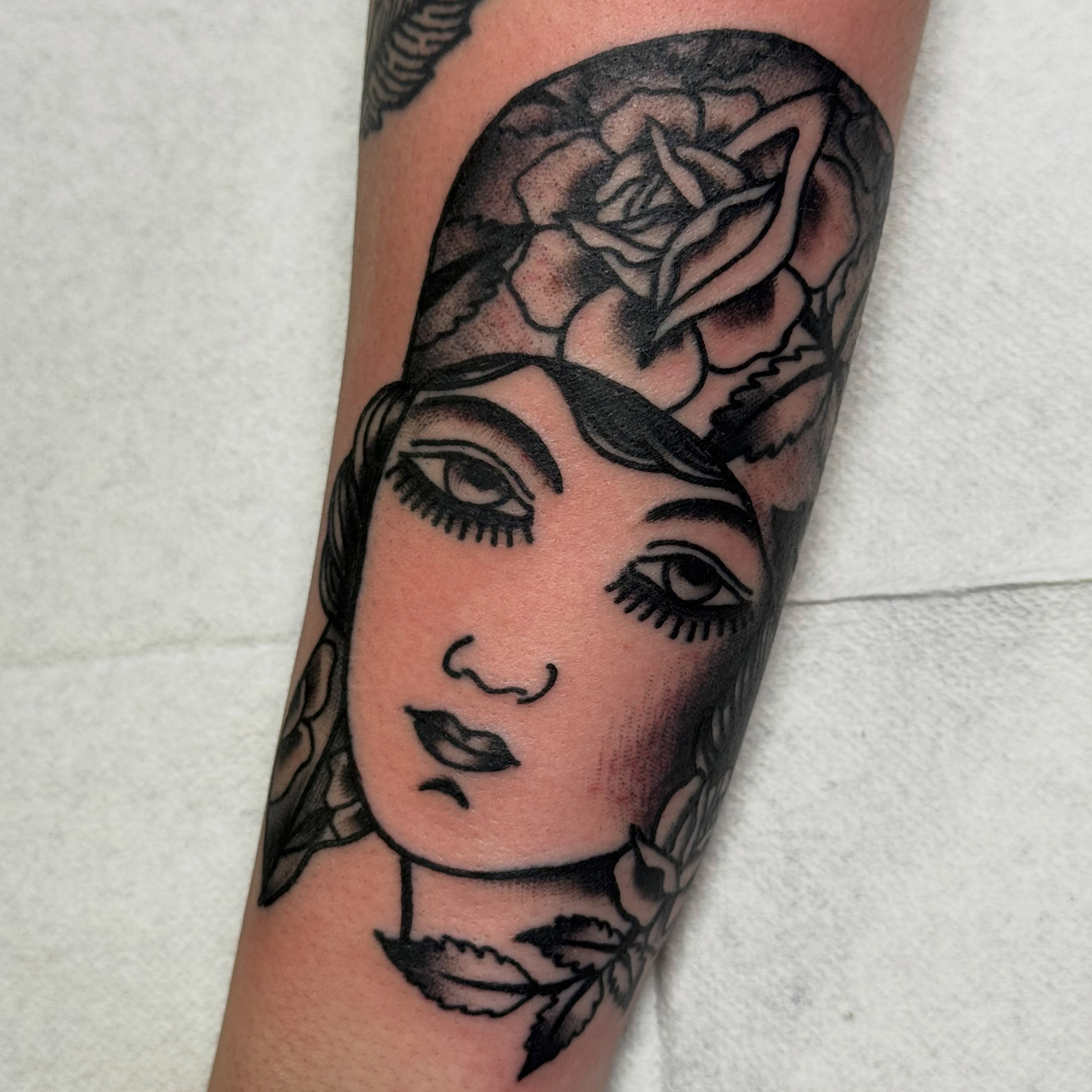Woman's face with rose American traditional tattoo on the forearm by Jack Hatchet Tattoos