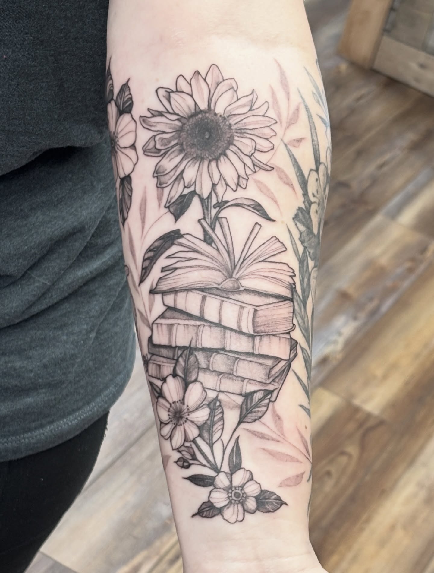 Sunflower and books realism tattoo on the forearm by MJ Saunders
