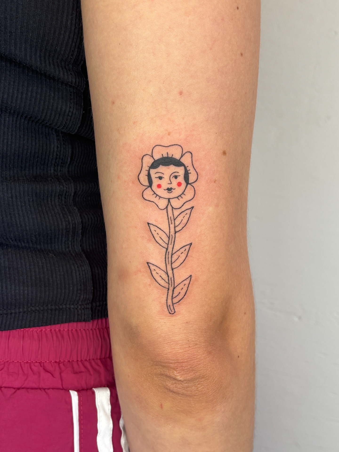 Flower with face illustrative tattoo on the forearm by Raye