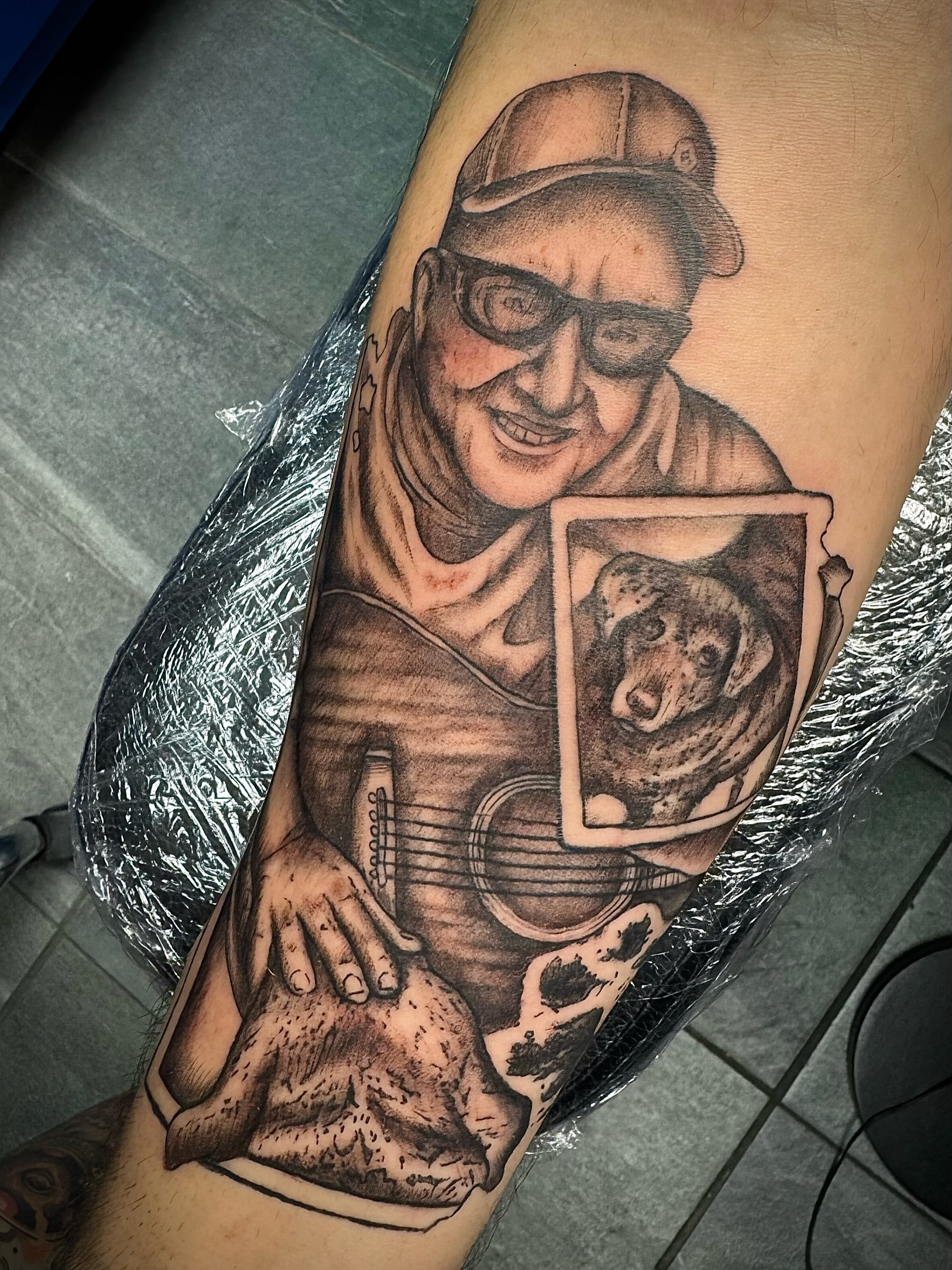 Elderly man with guitar realism tattoo on the forearm by Mikaila Jean
