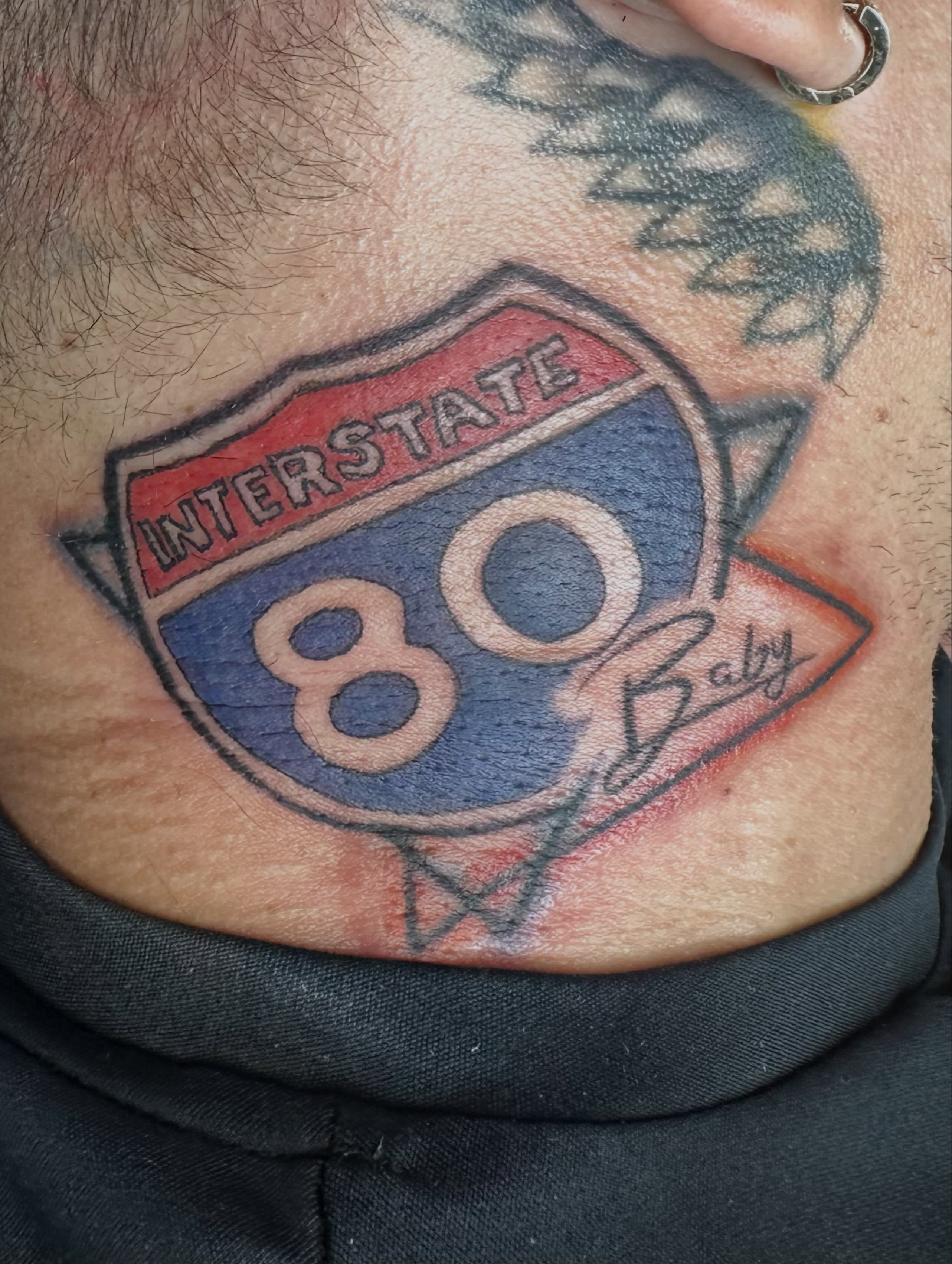 Interstate highway sign American traditional tattoo on the chest by Mikaila Jean