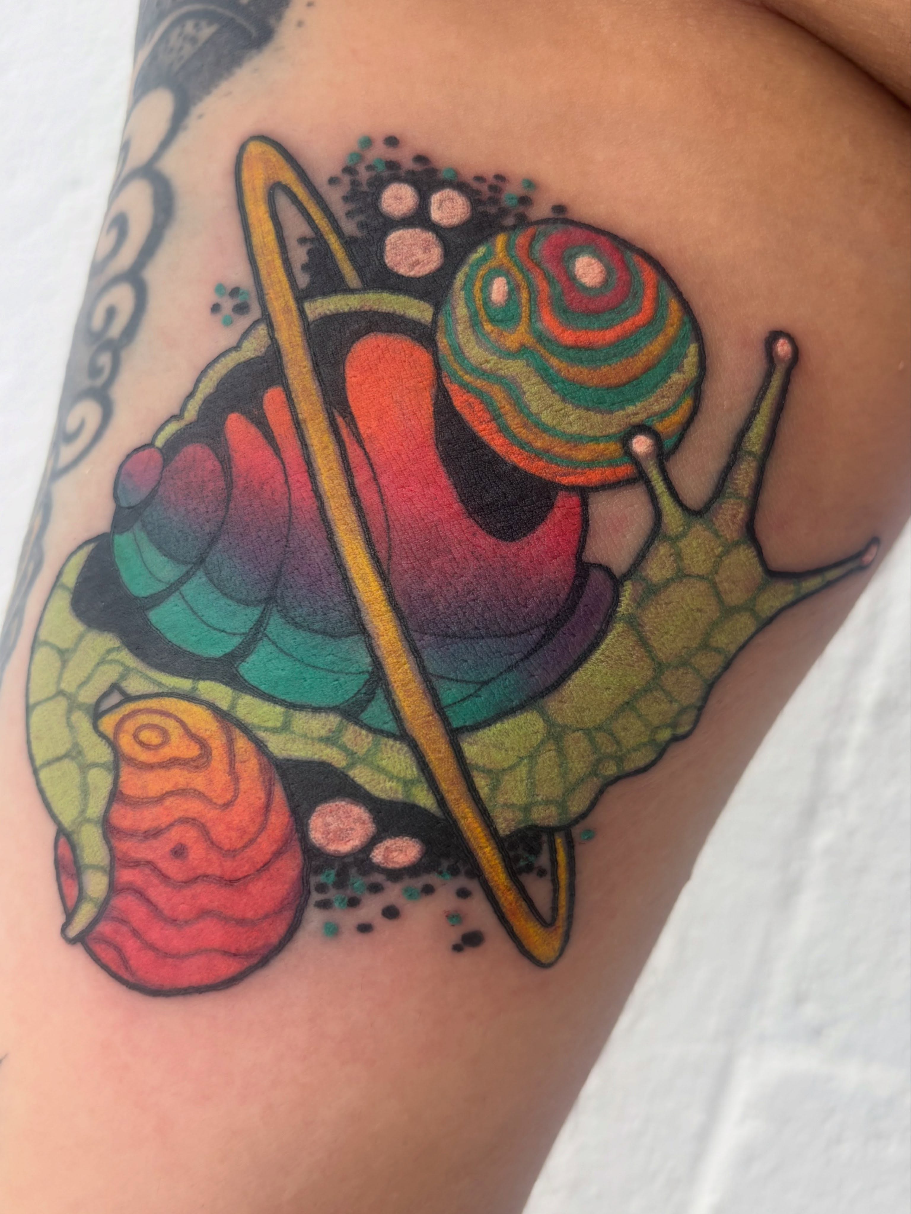 Snail and planet dotwork tattoo on the thigh by Carly Zehring