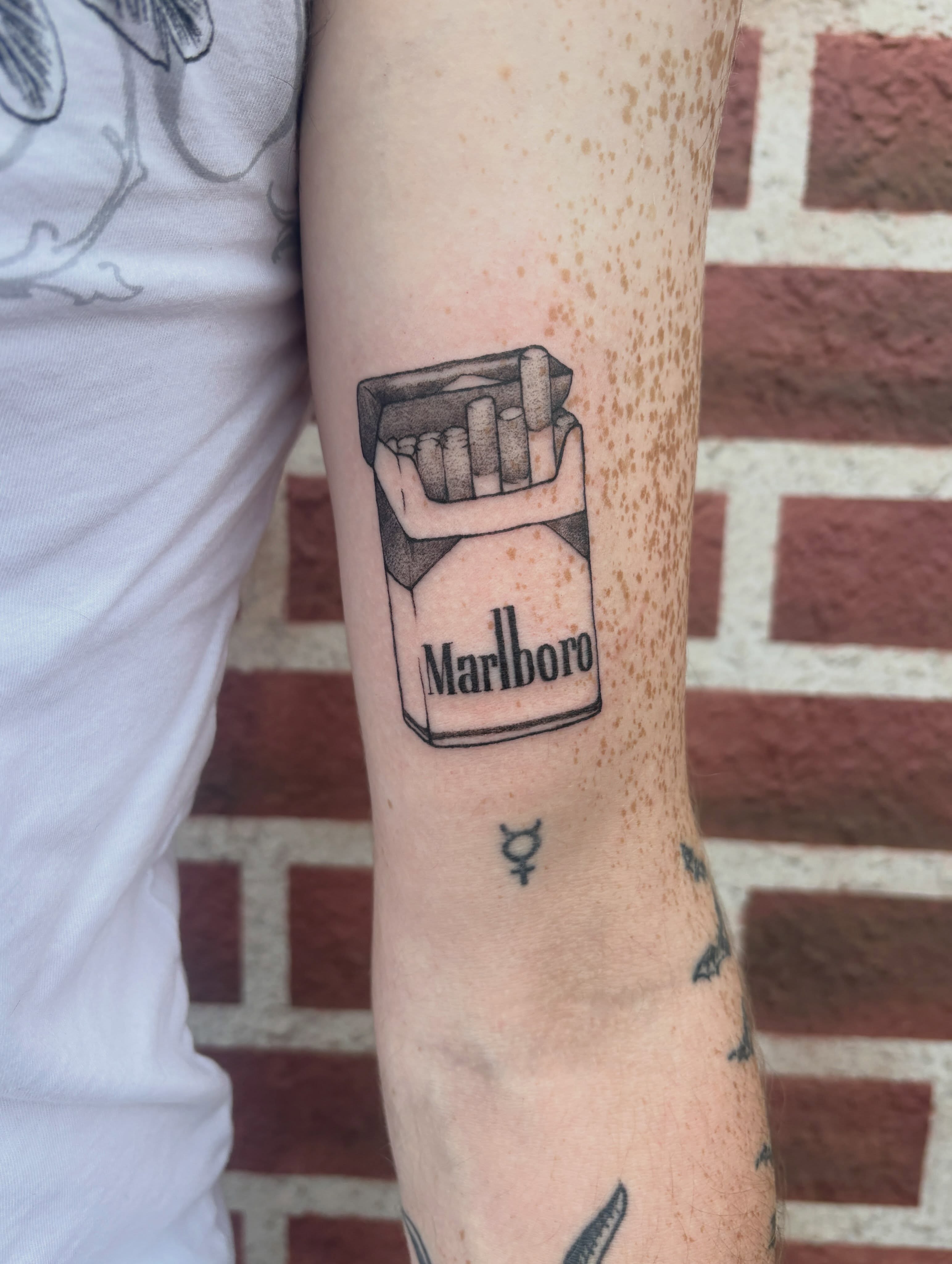 Marlboro cigarette pack black and grey tattoo on the forearm by izzy solae
