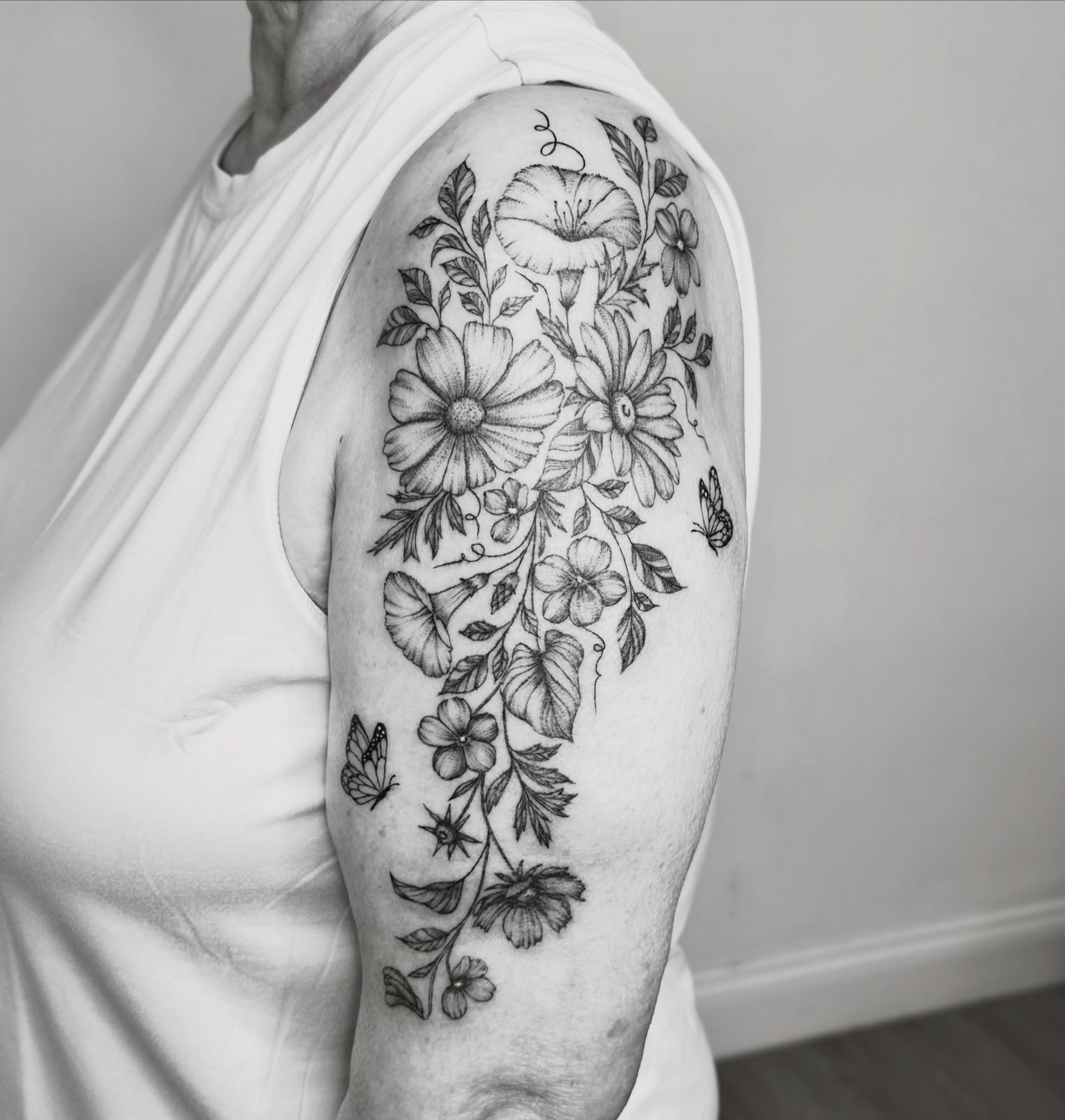 Floral bouquet realism tattoo on the upper arm by Fine Line Tattoo Artist