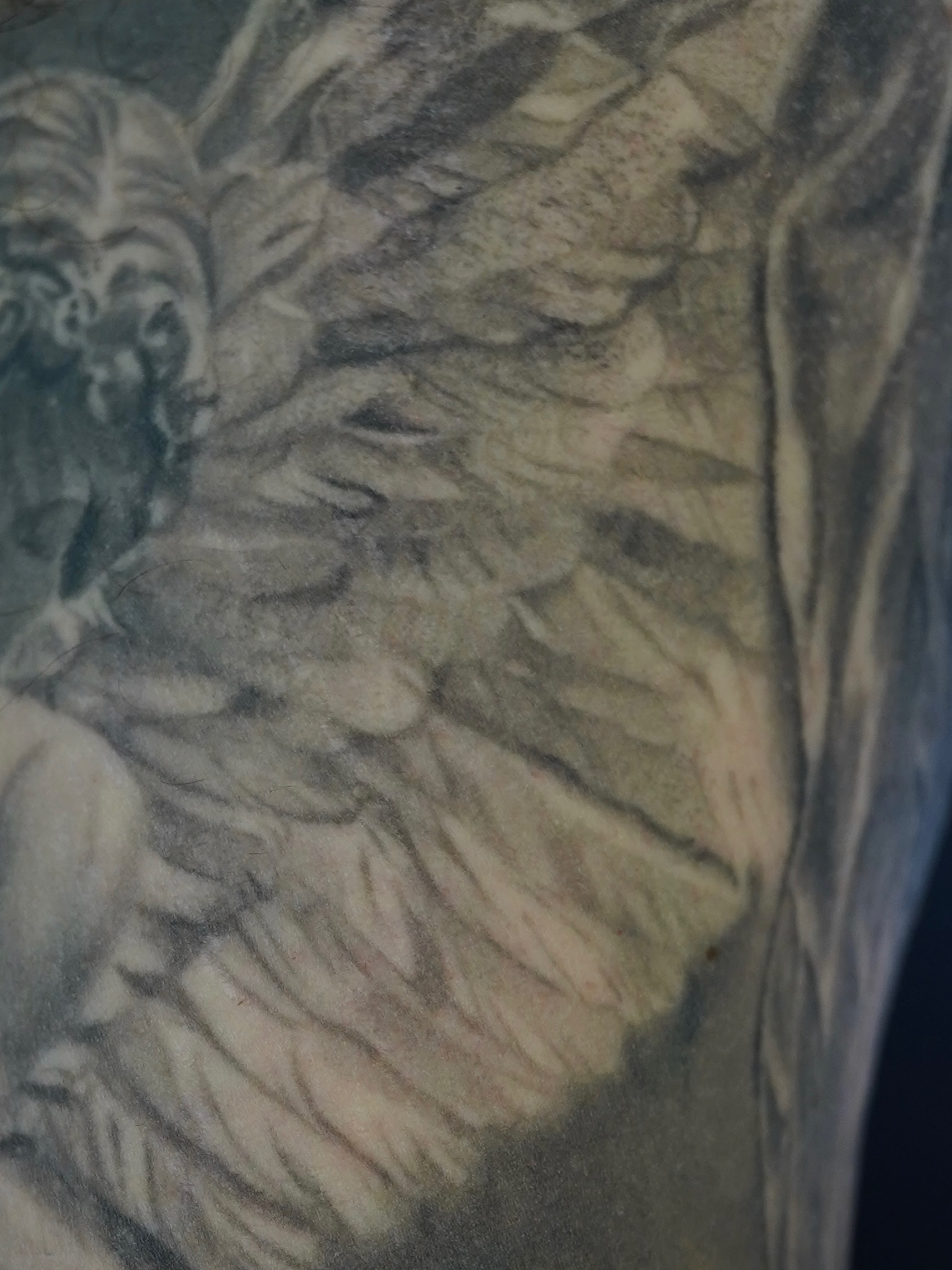 Angel wings black and grey tattoo on the upper arm by Eric RudeInk