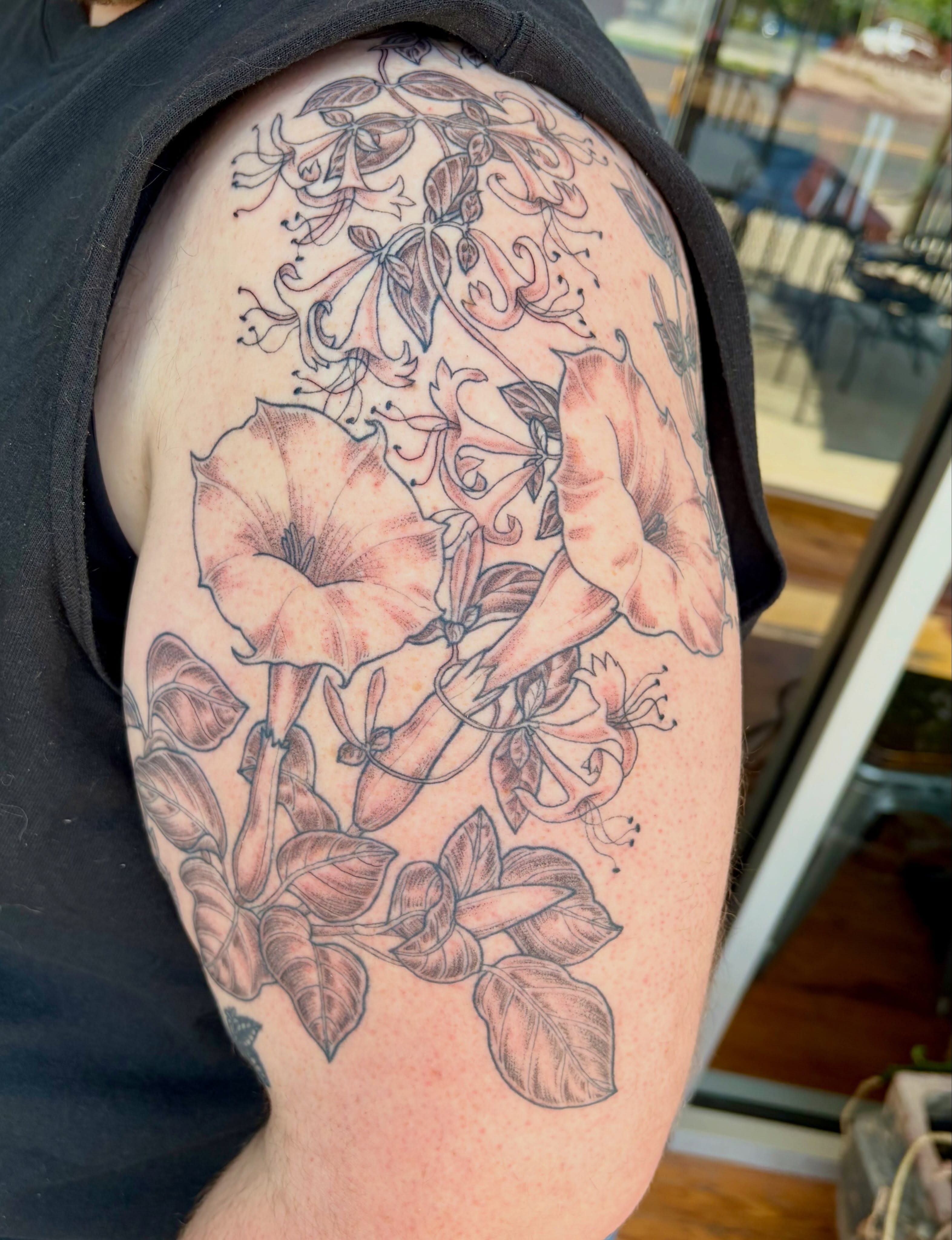 Morning glory flowers black and grey tattoo on the upper arm by Sarah Roach