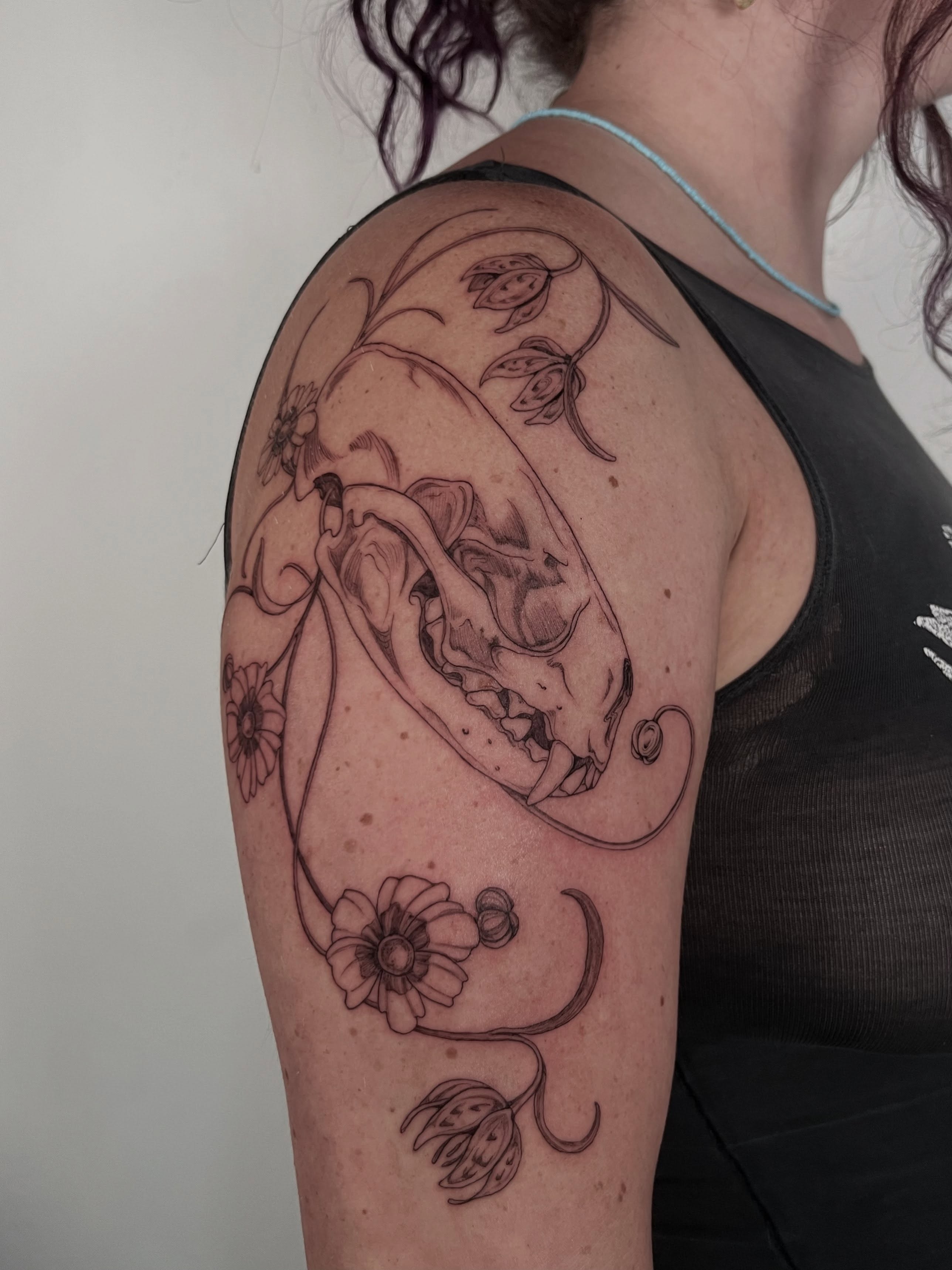 Skull and flowers realism tattoo on the shoulder by Sierra Skye