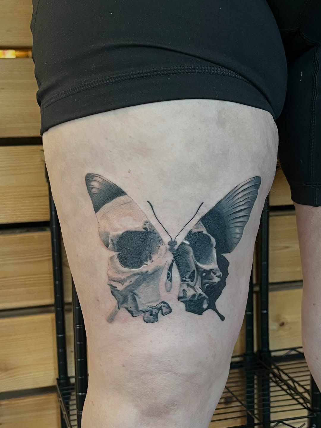 Skull butterfly fine line tattoo on the thigh by Hayes