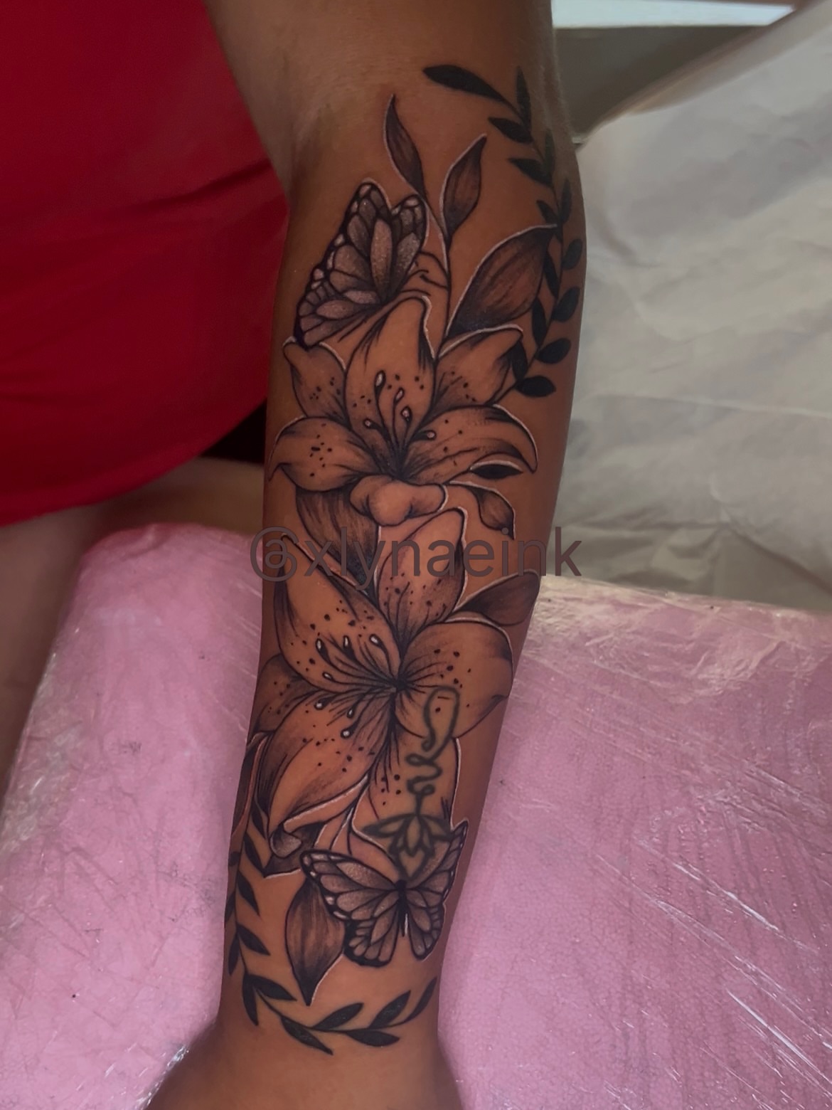 Lilies and butterflies realism tattoo on the forearm by The inspo